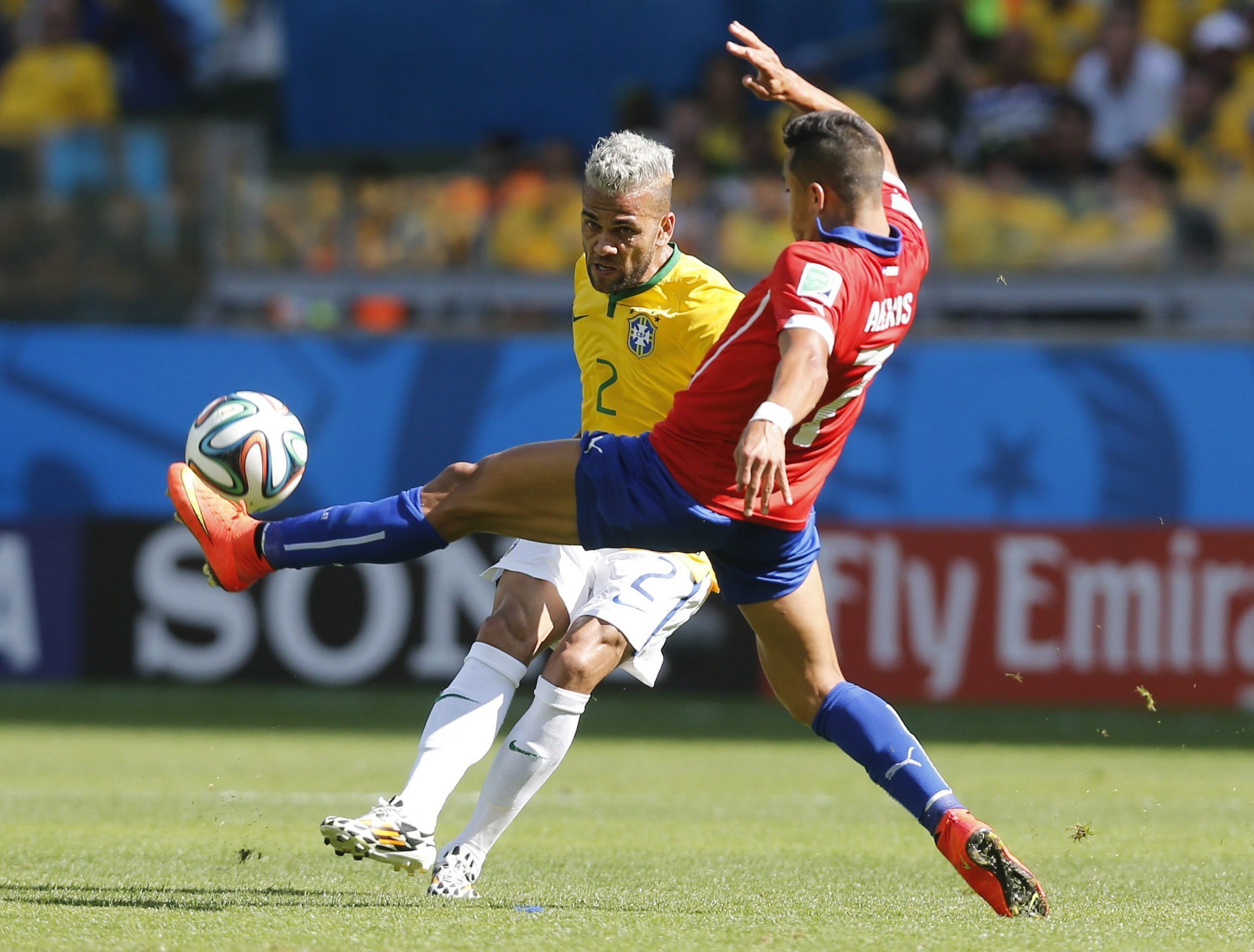 Dani Alves of Brazil vies with Alexis Sanchez of Chile during the match between Brazil and Chile at the Estadio Mineirao in Belo Horizonte, Brazil on June 28, 2014.