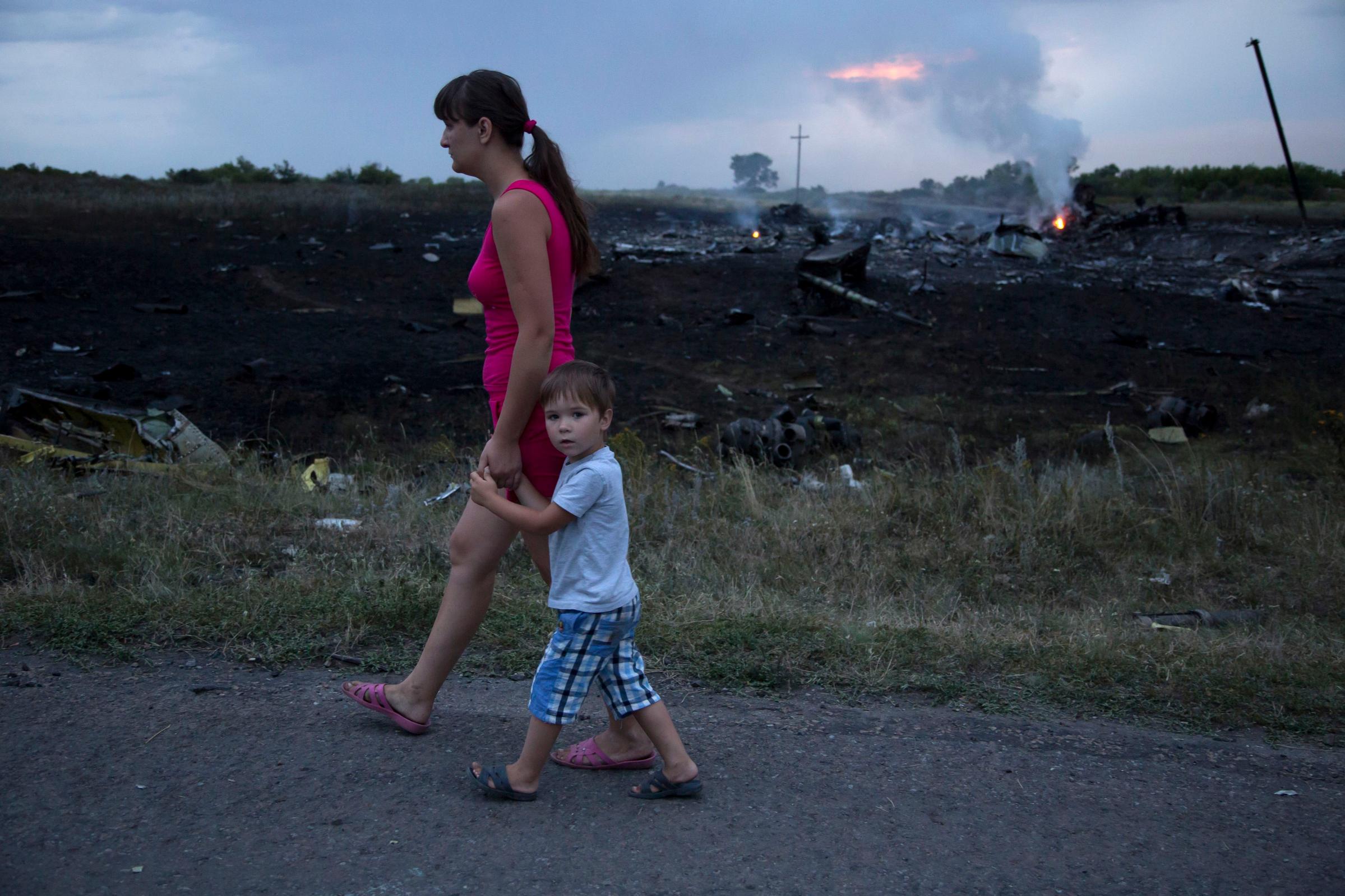 A woman and child walk past the crash site of a passenger plane near the village of Grabovo, Ukraine on Thursday, July 17, 2014.