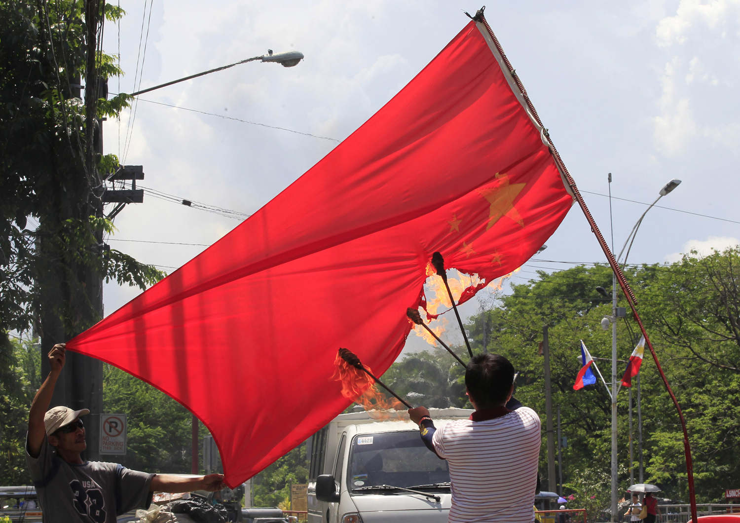 Abner Afuang, a retired policeman, sets fire to an inverted Chinese national flag in a protest action in Manila,