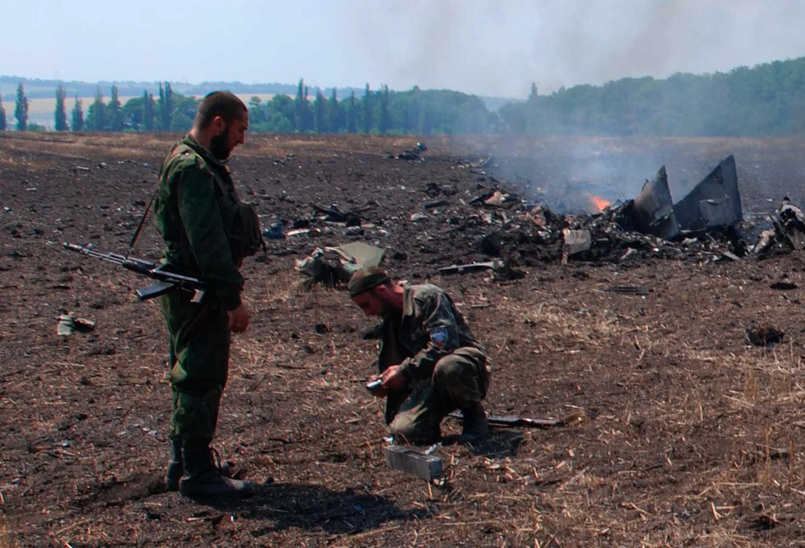In this framegrab made from a video provided by press service of the rebel Donetsk People's Republic and icorpus.ru, pro-Russians collect parts of the burning debris of a Ukrainian military fighter jet, shot down at Savur Mogila, eastern Ukraine, Wednesday, July 23, 2014. (icorpus.ru—AP)