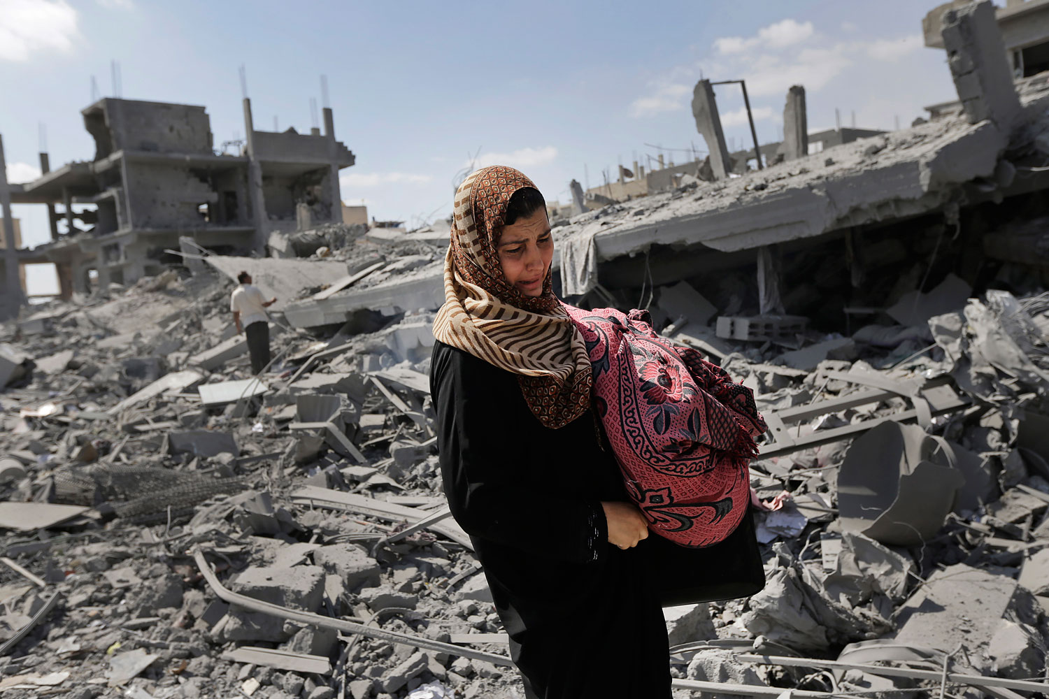 A Palestinian woman carries her belongings past the rubble of houses destroyed by Israeli strikes in Beit Hanoun, northern Gaza Strip, July 26, 2014. (Lefteris Pitarakis—AP)
