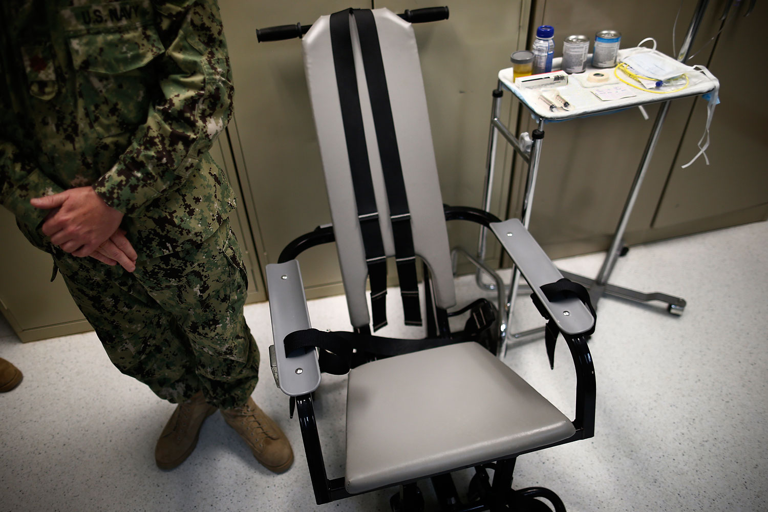 In this photo Nov. 20, 2013 file photo reviewed by the U.S. military, a U.S. Navy nurse stands next to a chair with restraints, used for force-feeding, and a tray displaying nutritional shakes, a tube for feeding through the nose, and lubricants, including a jar of olive oil, during a tour of the detainee hospital at Guantanamo Bay Naval Base in Cuba. (Charles Dharapak—AP)