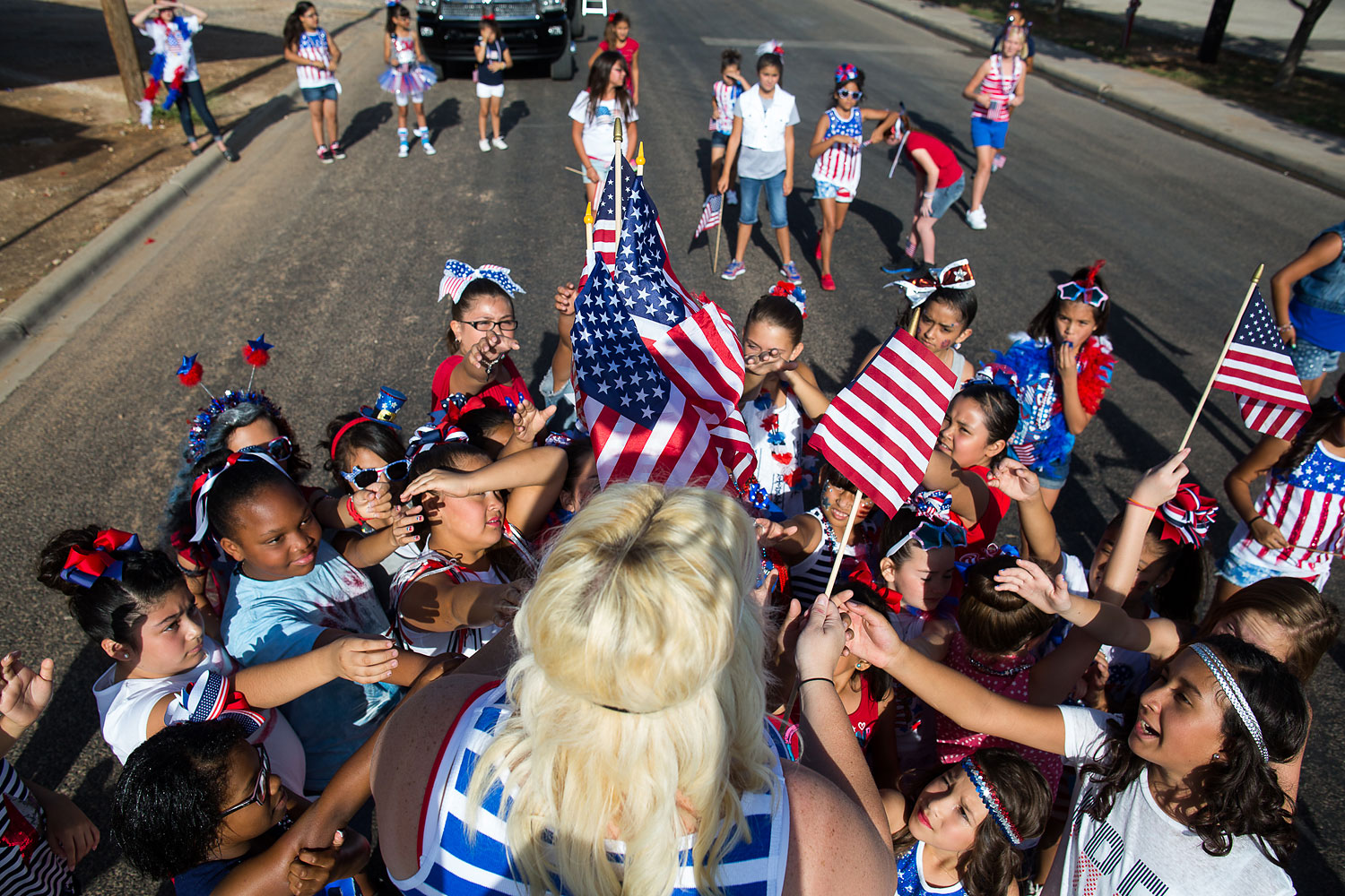 Elasha Ramirez hands out American flags before the 65th annual Jaycees Independence Day parade, July 4, 2014, in Odessa, Texas.