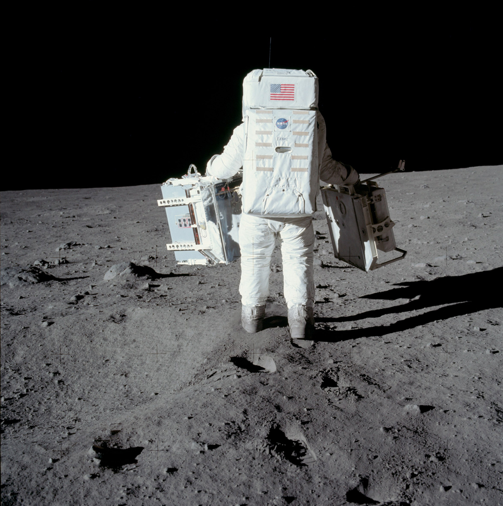 This photograph is the first in a sequence of pictures Neil took of Buzz carrying the EASEP out to the deployment site a short way south of the spacecraft.