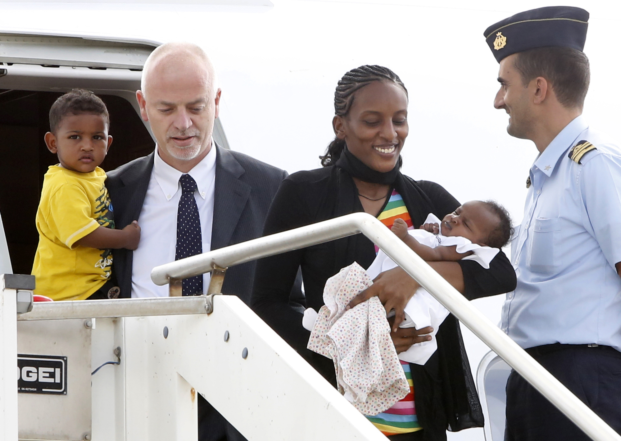 Mariam Ibrahim, from Sudan, disembarks with her children Maya, in her arms, and Martin, accompanied by Italian deputy Foreign Minister Lapo Pistelli, after landing from Khartoum, at Ciampino's military airport, on the outskirts of Rome, Thursday, July 24. (Riccardo De Luca—AP)