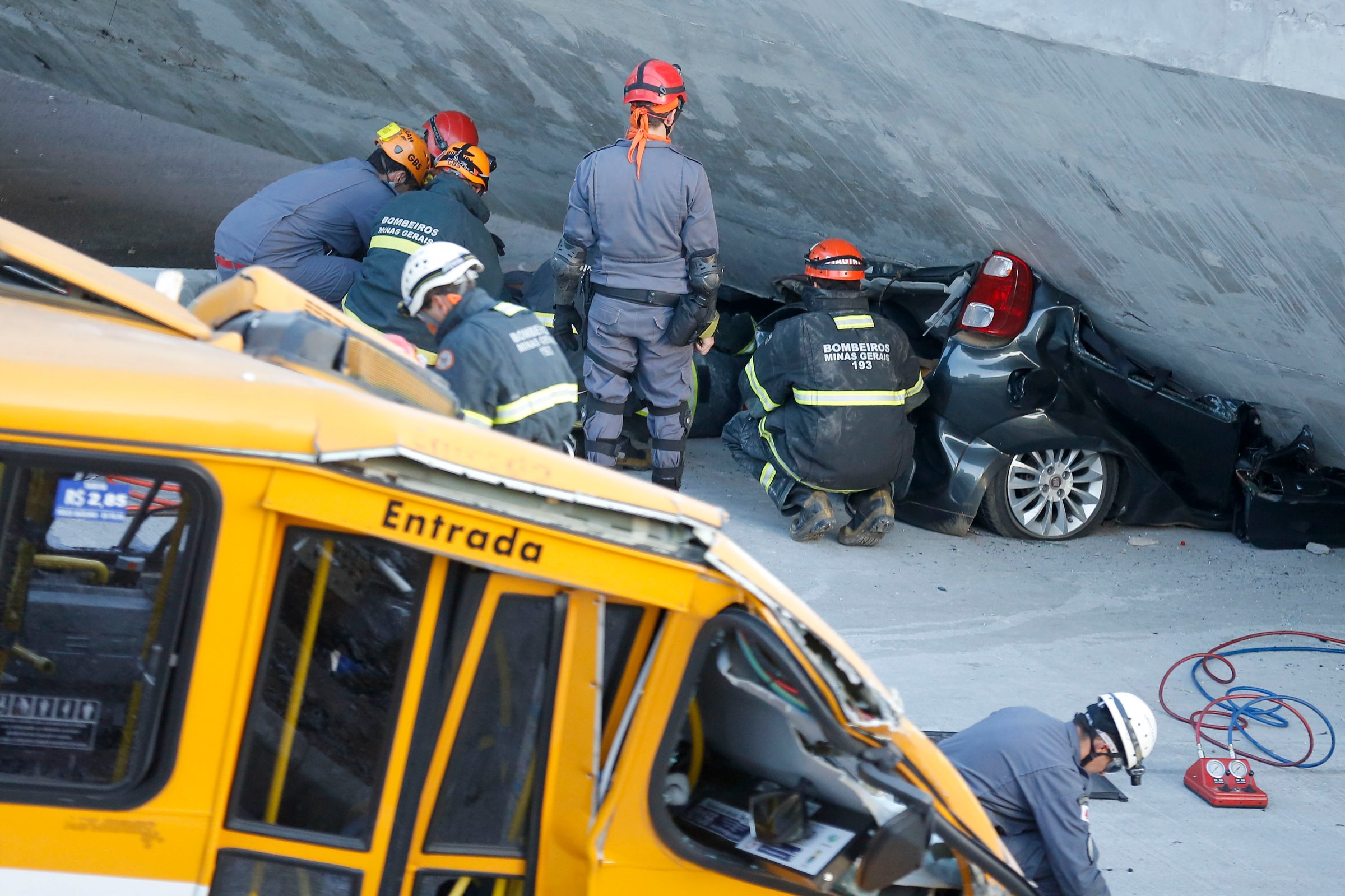Fire department personnel work to retrieve a car from underneath a collapsed bridge in Belo Horizonte, Brazil, Thursday, July 3, 2014.
