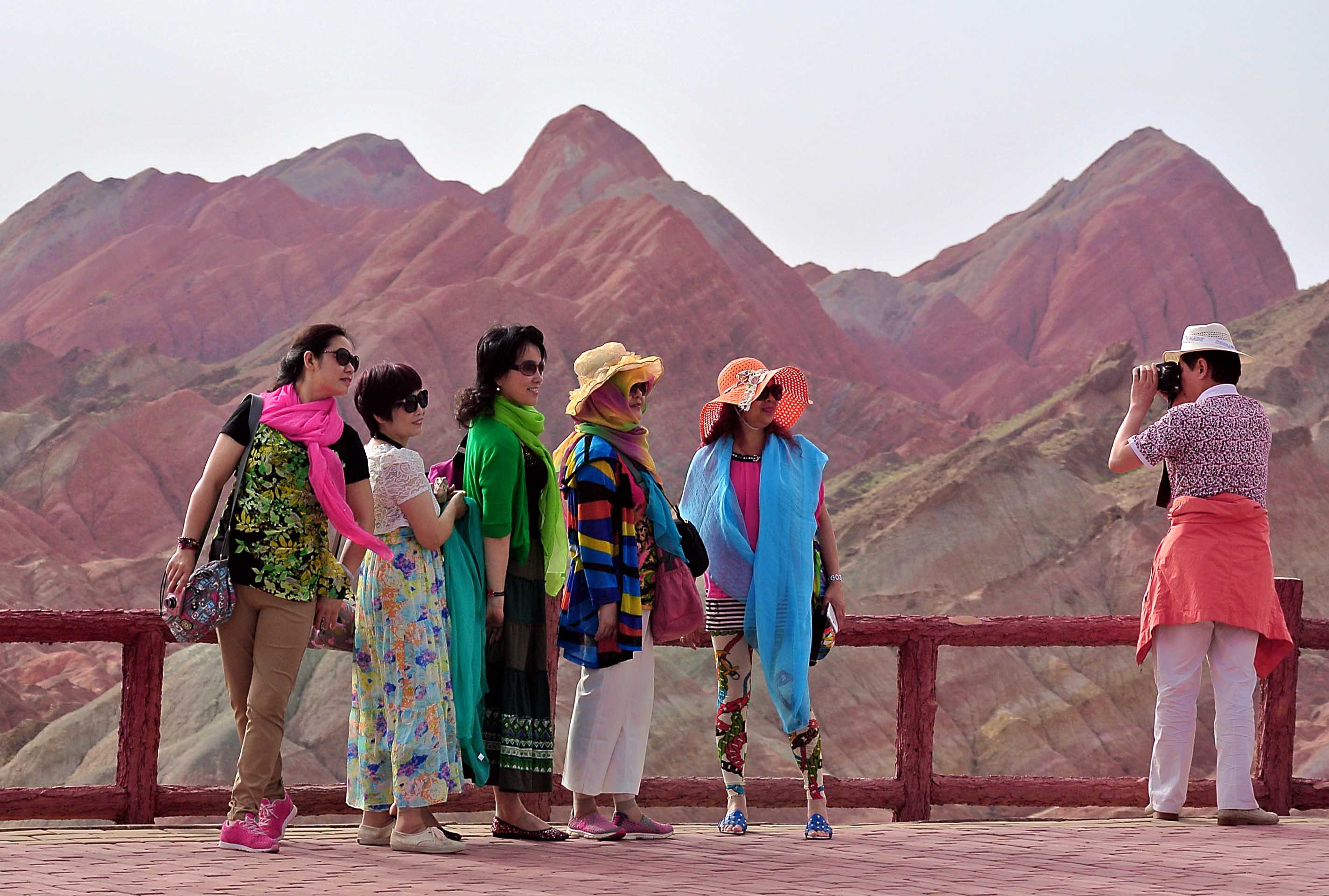 Visitors take photos at Zhangye Danxia Landform Geological Park in Zhangye City, Gansu Province, northwest China, July 7, 2014.
