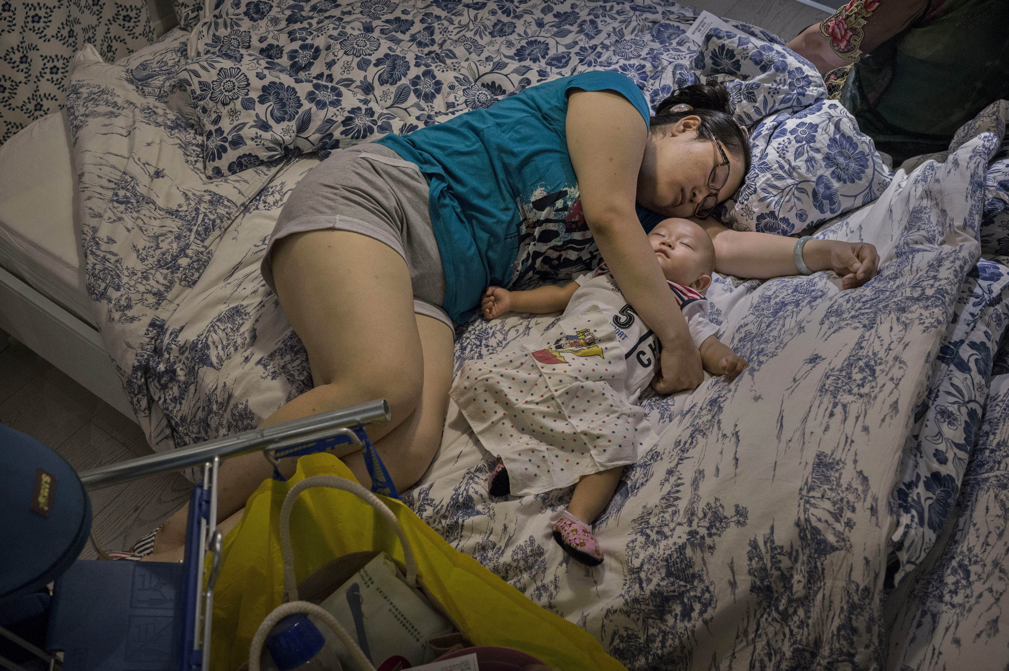A shopper sleeps with her child on a bed in the showroom of the IKEA store on July 6, 2014 in Beijing.