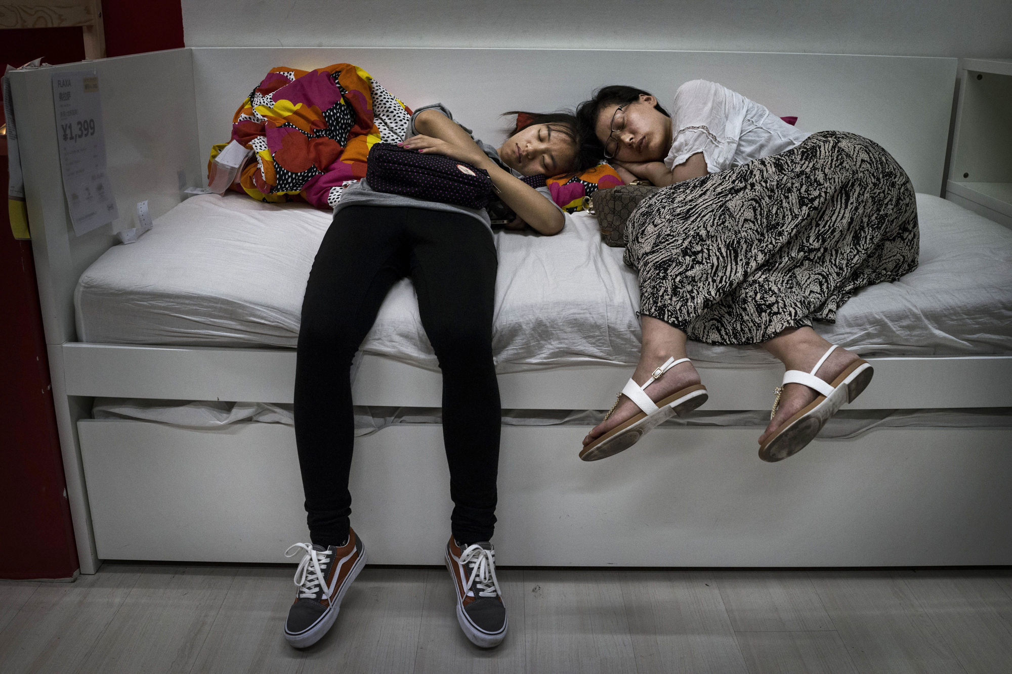 Shoppers sleep on a bed in the showroom of the IKEA store on July 6, 2014 in Beijing.