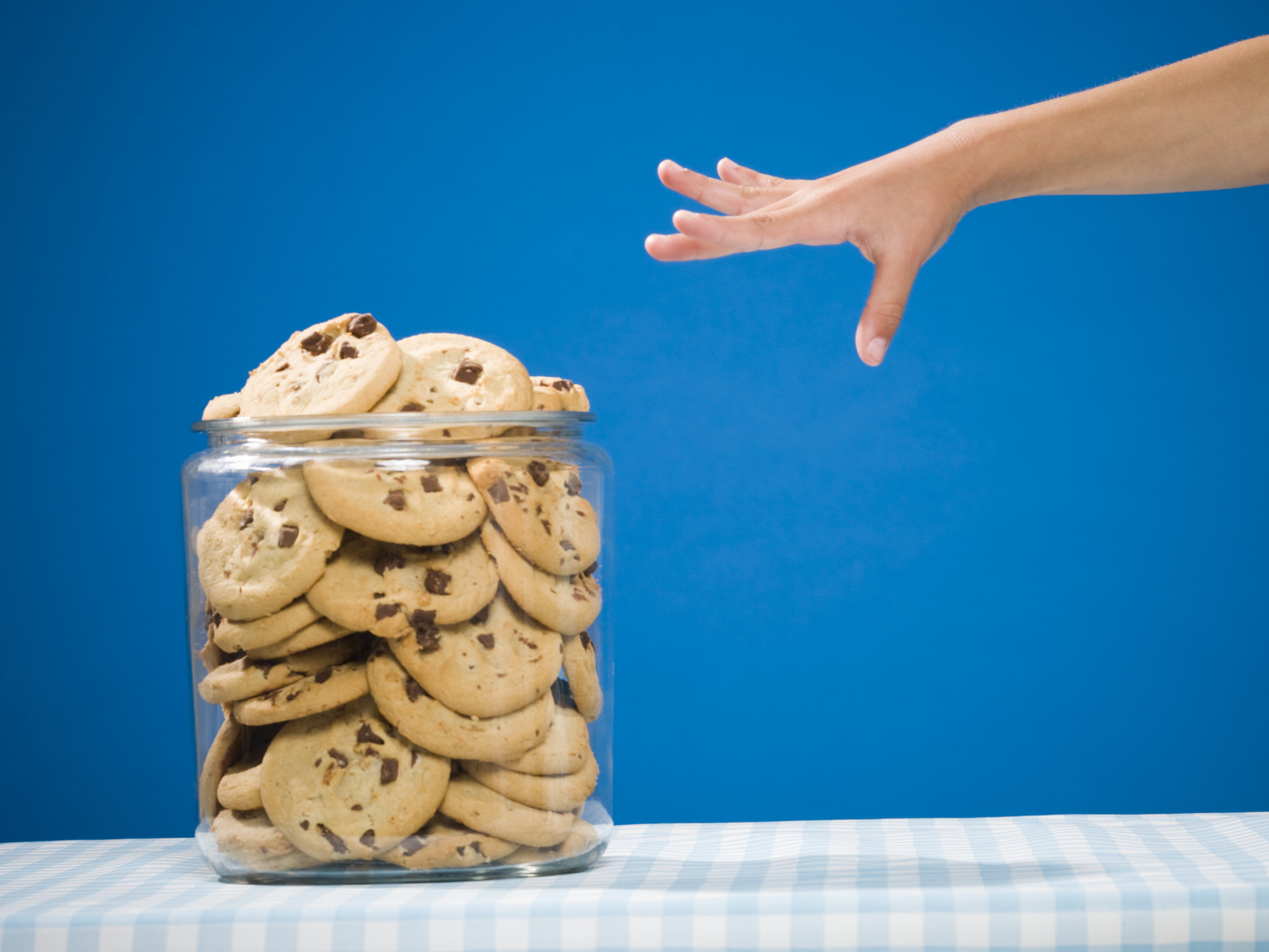 Hand reaching for chocolate chip cookie jar (Mike Kemp—Rubberball/Getty Images)