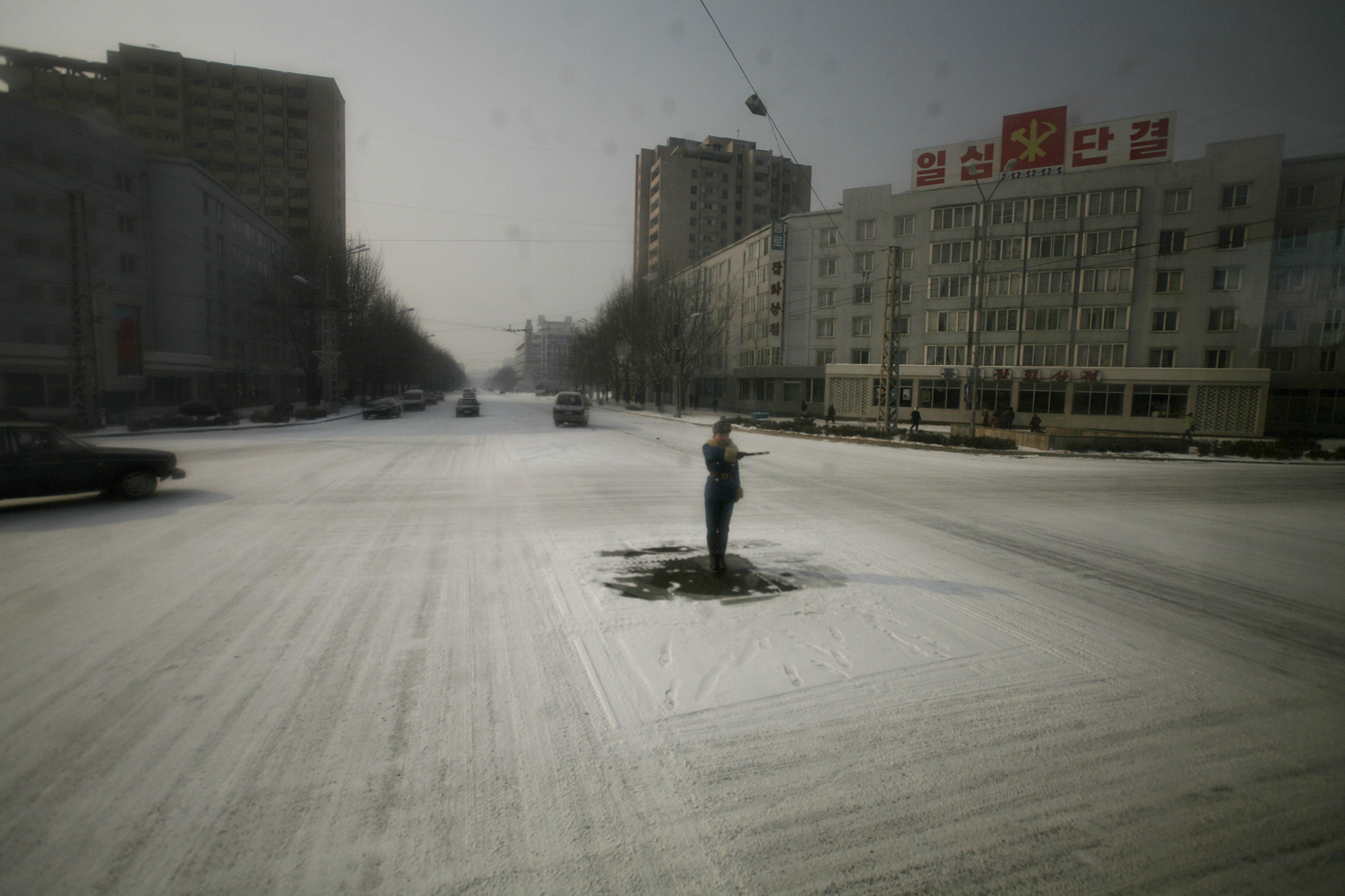 A traffic guard stands in the center of a snowy street in Pyongyang, North Korea on Feb. 26, 2008.
