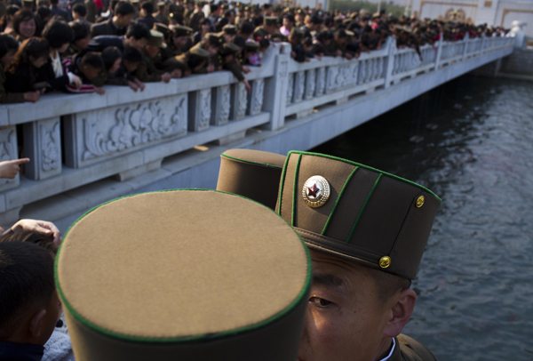 North Korean soldiers and civilians stand on a foot bridge to look at goldfish in a moat as they tour the grounds of Kumsusan Palace of the Sun, the mausoleum where the bodies of the late leaders Kim Il Sung and Kim Jong Il lie embalmed, in Pyongyang on April 25, 2013.