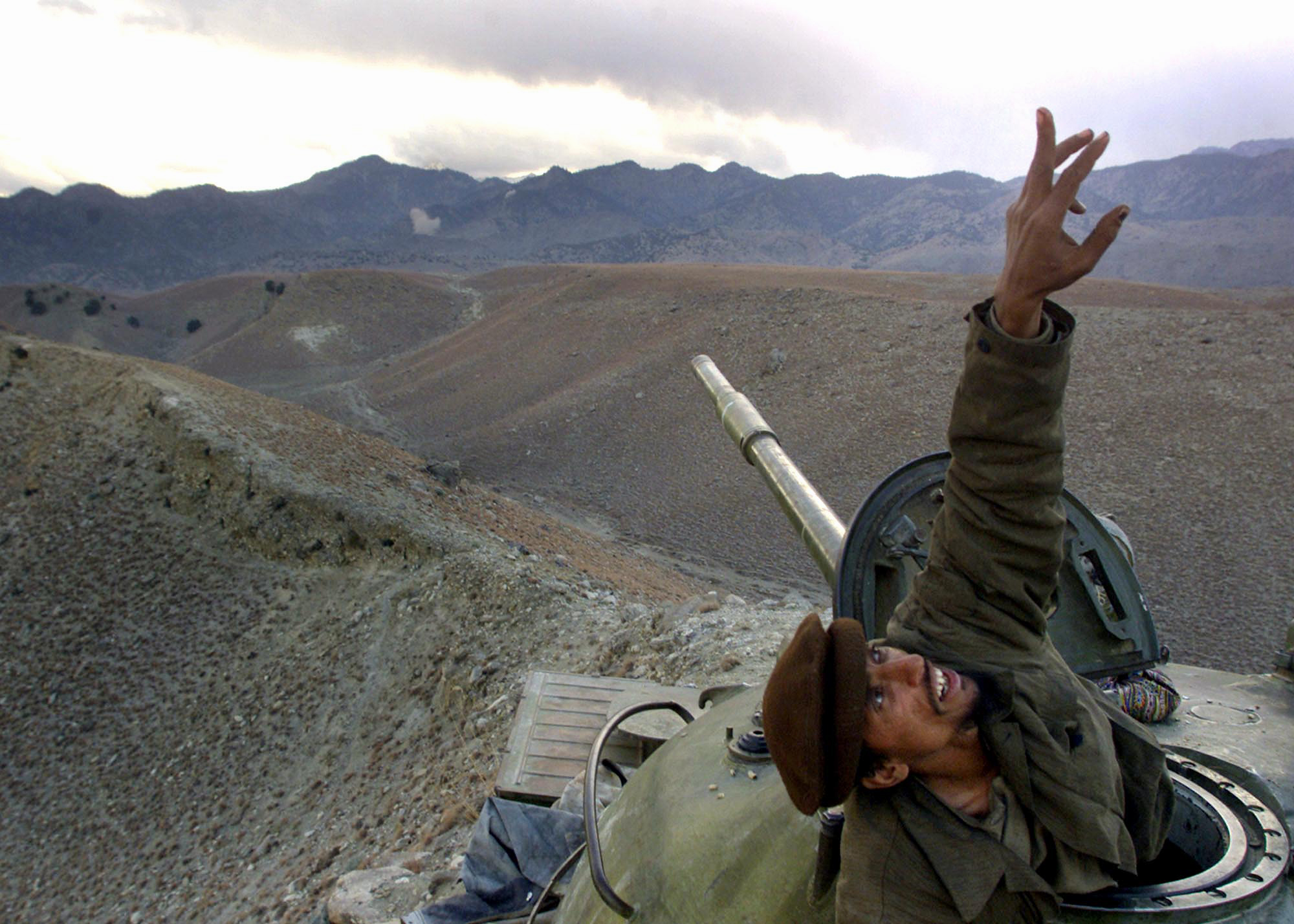 An Afghan anti-Taliban fighter pops up from his tank to spot a U.S. warplane bombing the al-Qaida fighters in the White Mountains of Tora Bora in Afghanistan, Dec. 10, 2001.
