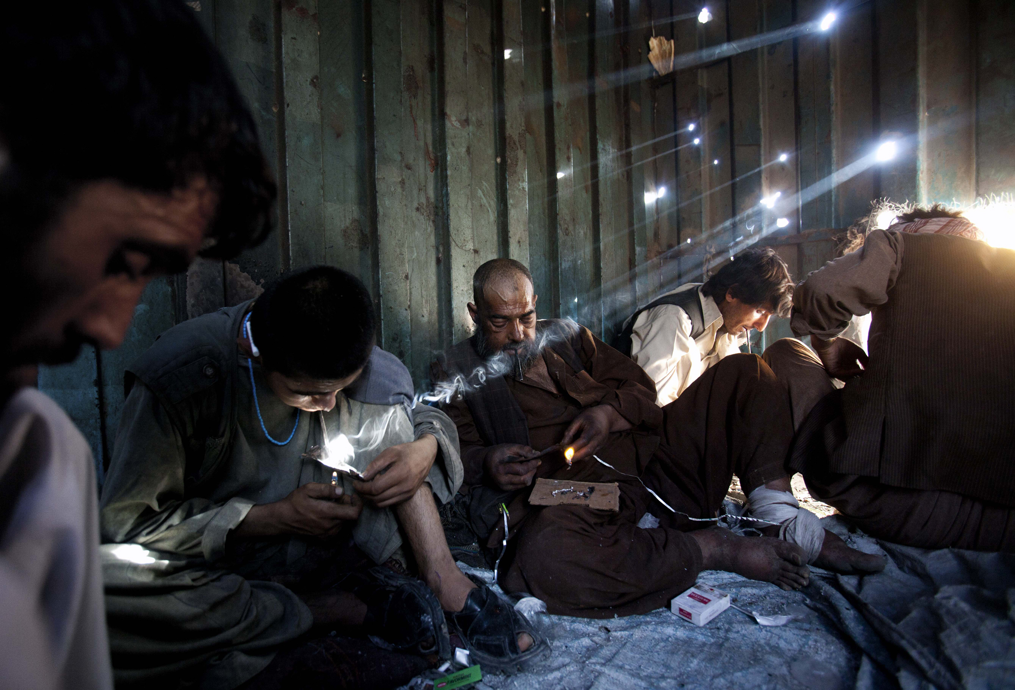 Sunlight pours through shrapnel holes in a shipping container in Kabul's Old City, where users gather for a hit of opium, June 23, 2010.