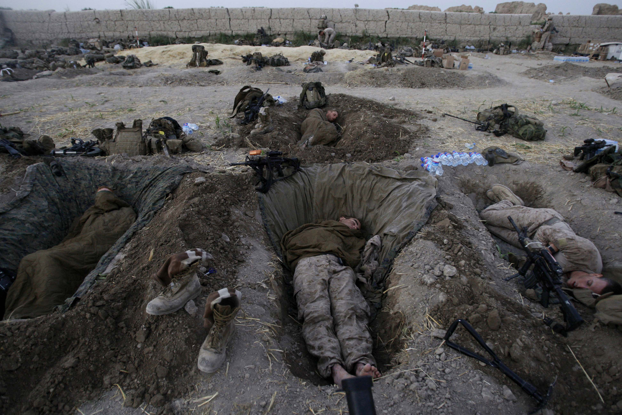 U.S. Marines from the 2nd MEB, 1st Battalion 5th Marines sleep in their fighting holes inside a compound where they stayed for the night, in the Nawa district of Afghanistan's Helmand province,  July 8, 2009.