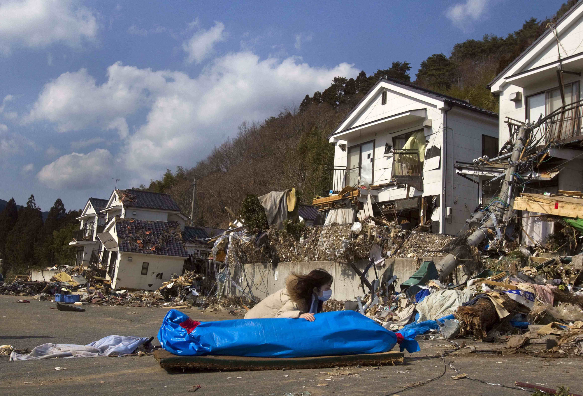 Tayo Kitamura, 40, kneels in the street to caress and talk to the wrapped body of her mother Kuniko Kitamura, 69, after Japanese firemen discovered the dead woman inside the ruins of her home in Onagawa, northeastern Japan, March 19, 2011.