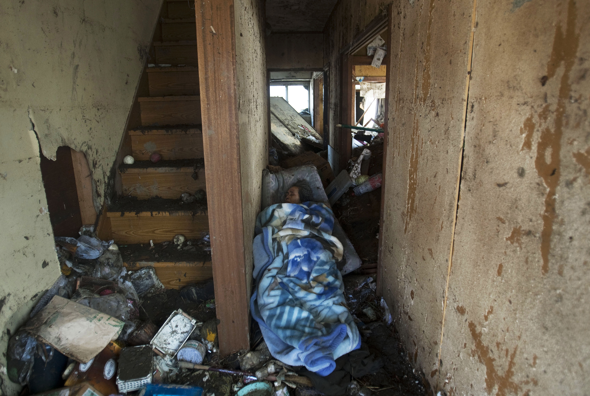 A dead woman lies under a blanket near the stairs of her destroyed home in Sendai, northeastern Japan, on March 13, 2011.