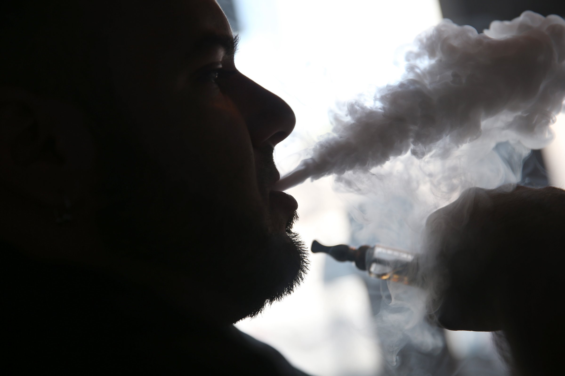 A salesman waits for customers as he enjoys an electronic cigarette at a store in Miami, Florida on April 24, 2014.