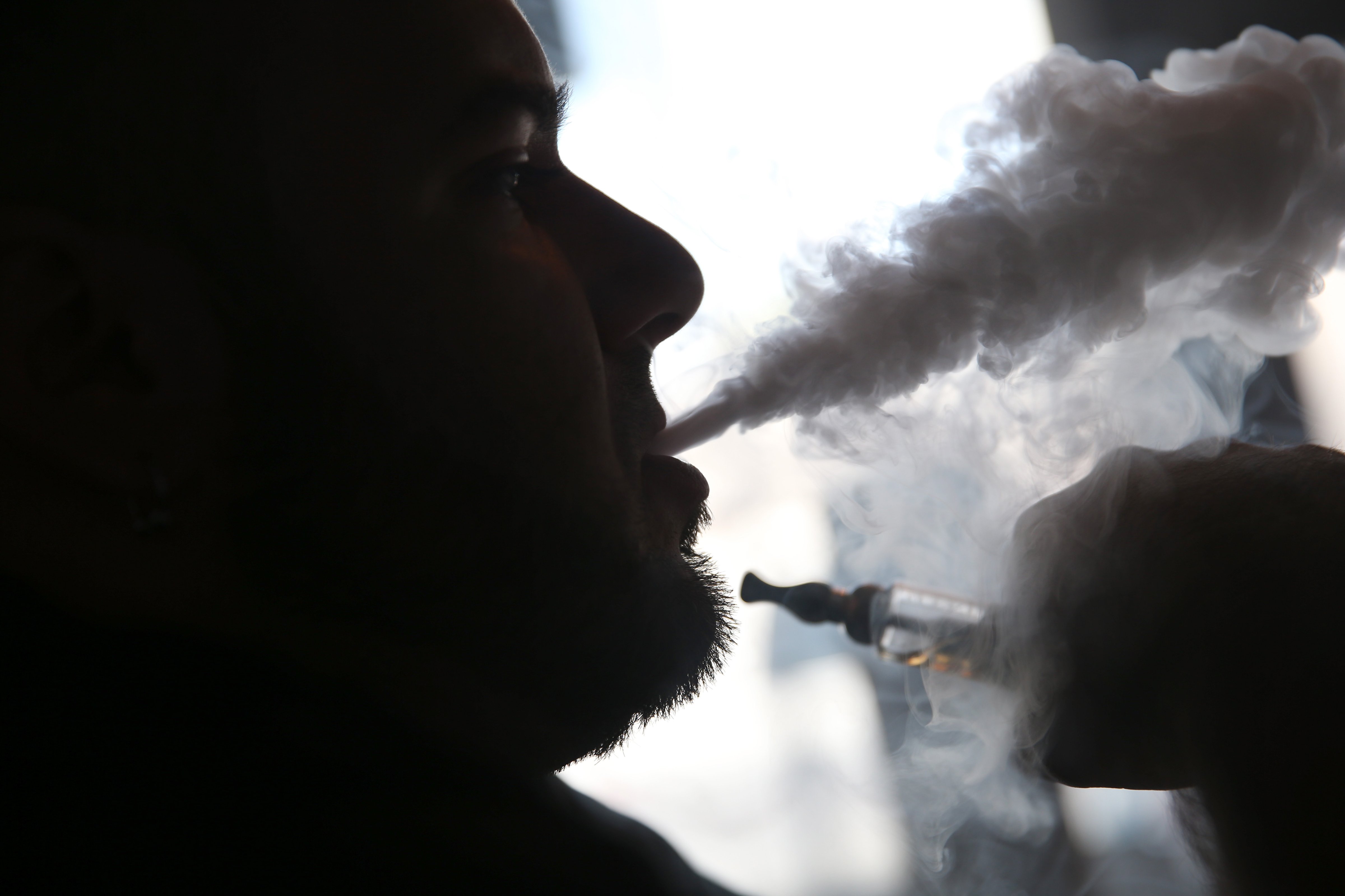 A salesman waits for customers as he enjoys an electronic cigarette at a store in Miami, Florida on April 24, 2014. (Joe Raedle—Getty Images)