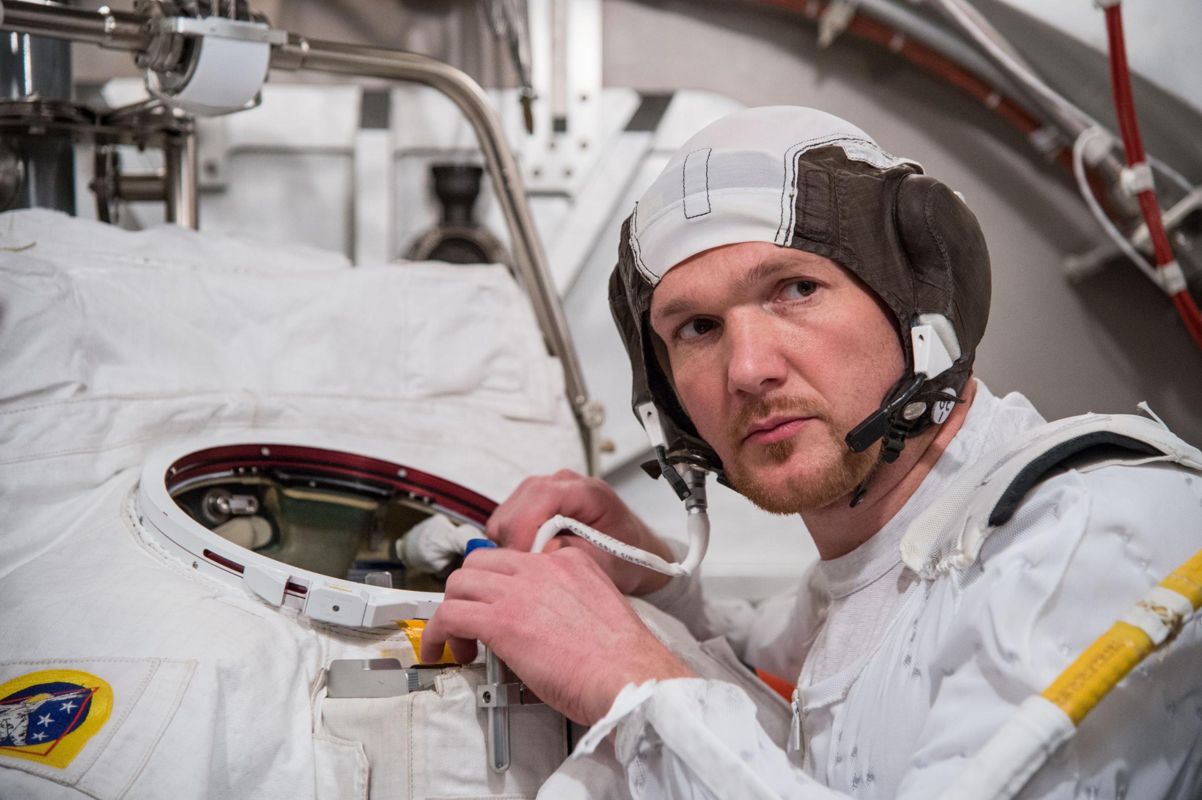 Astronaut Alexander Gerst participates in an Extravehicular Mobility Unit (EMU) spacesuit fit check, in the Space Station Airlock Test Article (SSATA) of the Crew Systems Laboratory at NASA's Johnson Space Center.