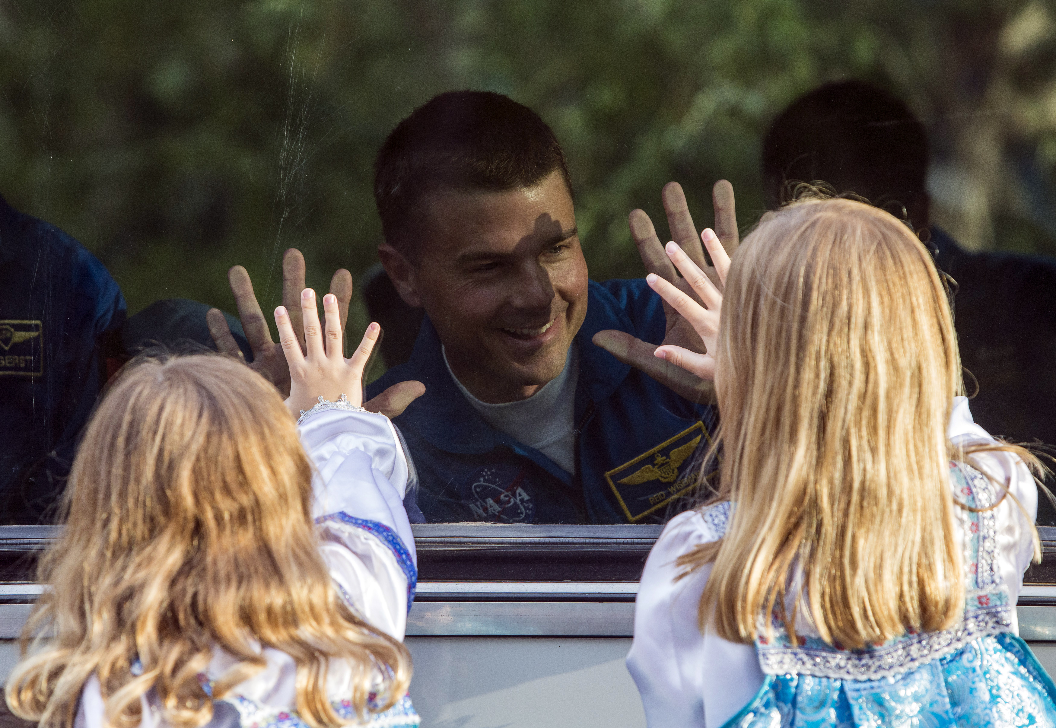 Reid Wiseman a member of the International Space Station crew, waves to his daughters from a bus before departure for a final pre-launch preparation at the Baikonur cosmodrome in Kazakhstan on May 28, 2014.