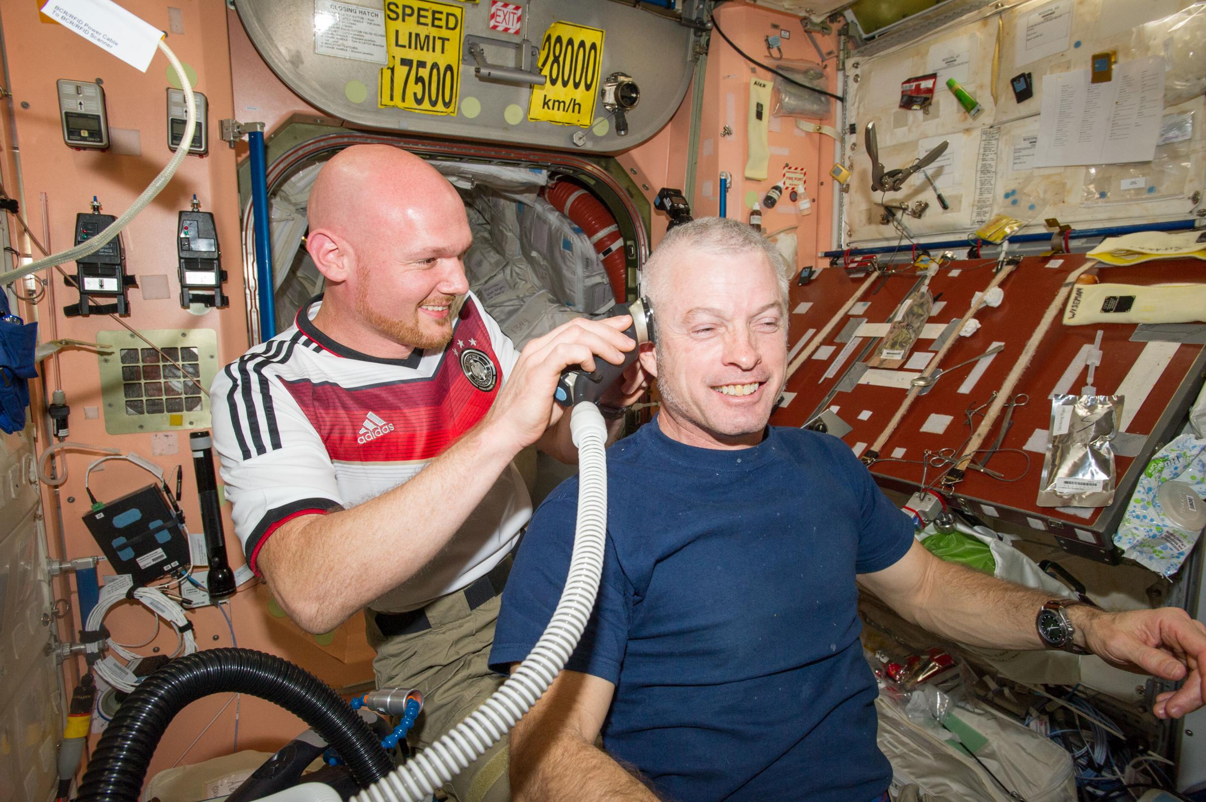 Astronaut Alexander Gerst, Expedition 40 flight engineer, shaves the head of NASA astronaut Steve Swanson in the Unity node of the International Space Station. Gerst used hair clippers fashioned with a vacuum device.