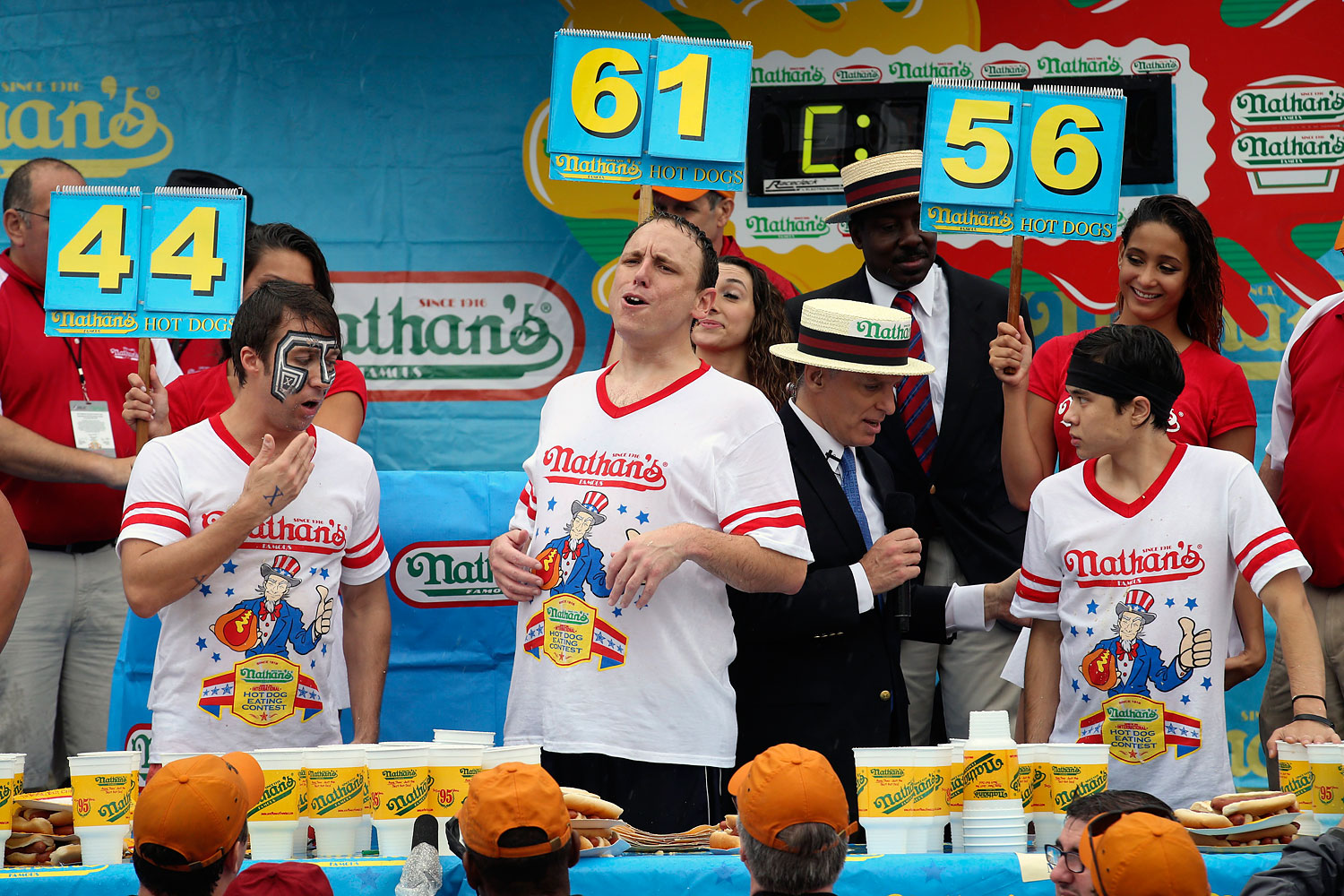 Joey Chestnut, center, reacts alongside Tim Janus, left, and Matt Stonie, right, after consuming a total of 61 hot dogs in ten minutes.