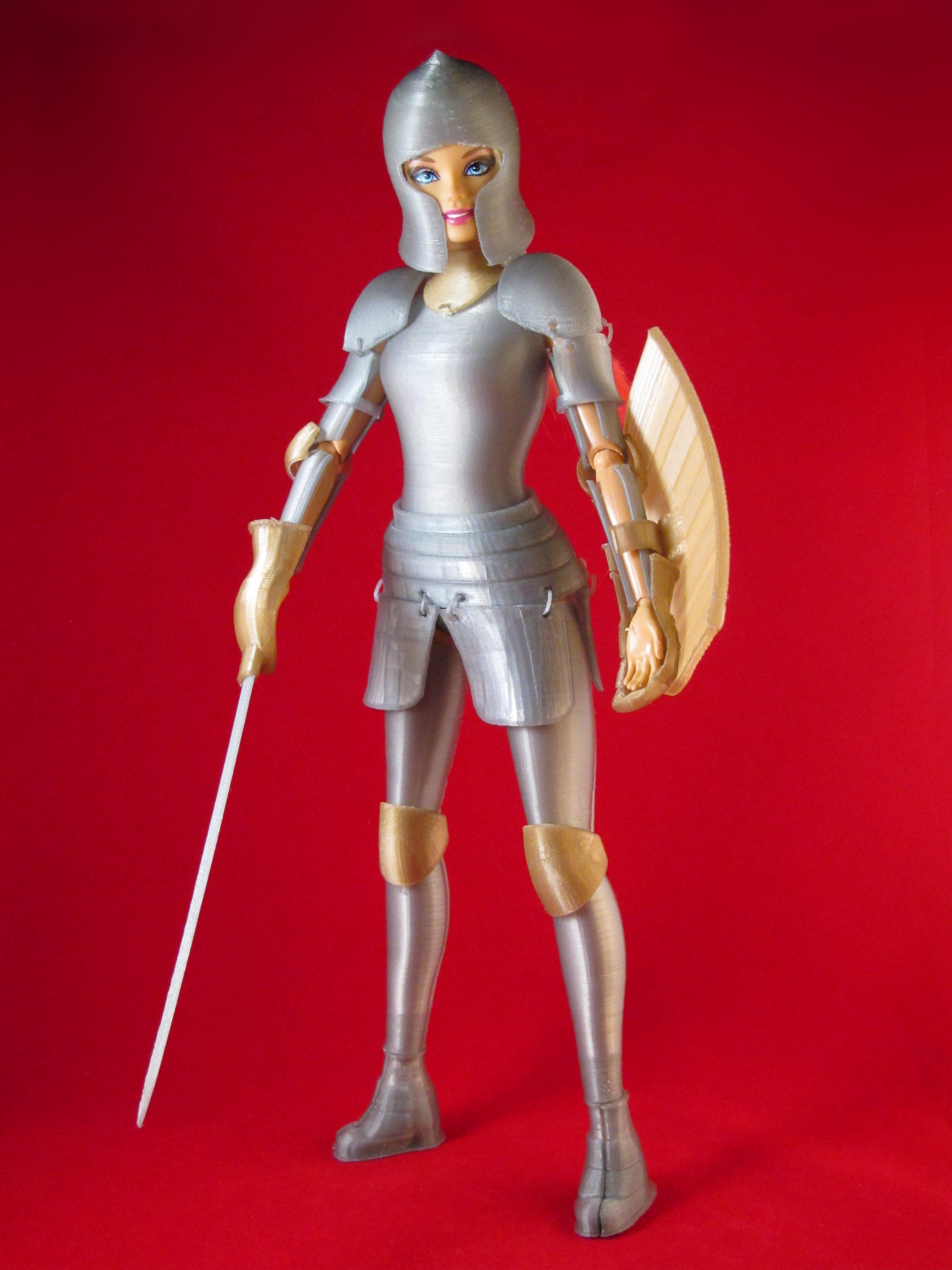 Barbie stands in her silver suit of armor, complete with shield and sword.
