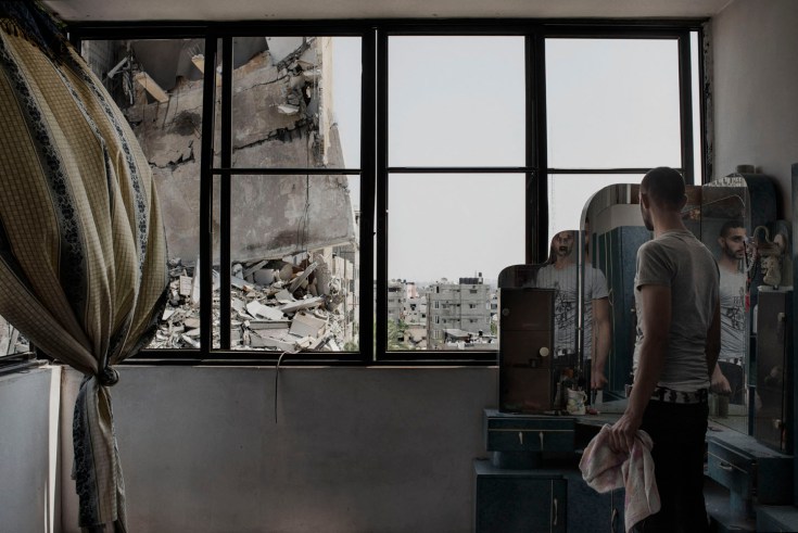 A Palestinian man looks through the window of his house to buildings damaged by an overnight airstrike in Gaza City, July 22, 2014. (Alessio Romenzi for TIME)