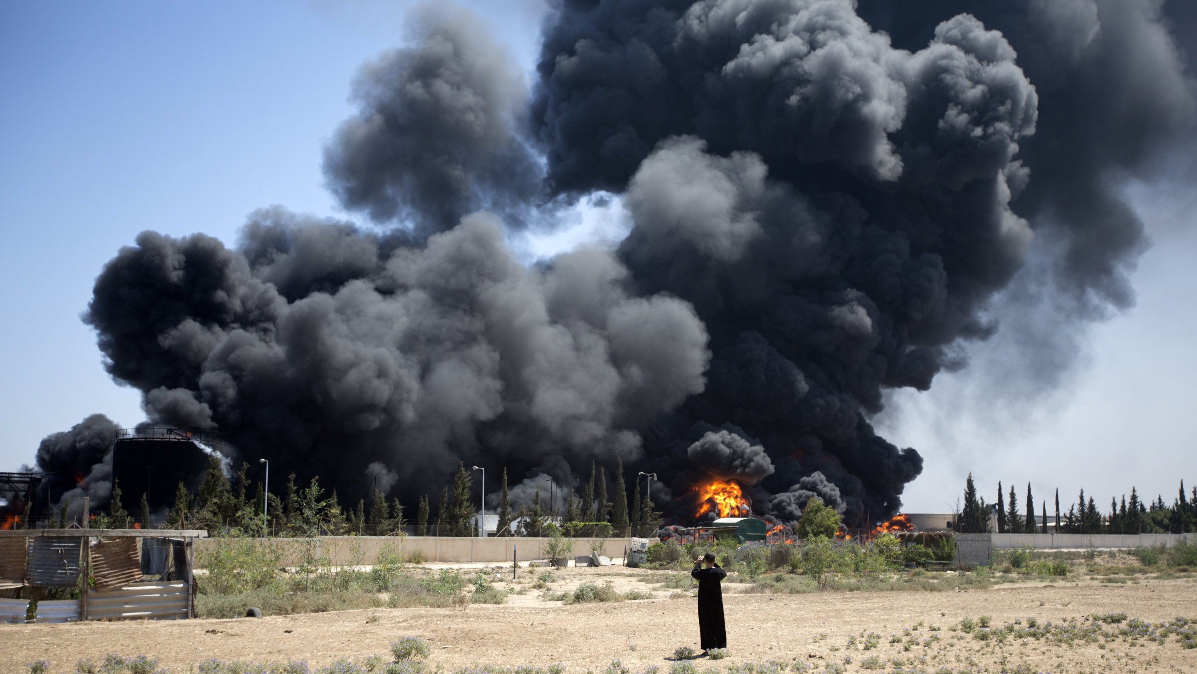 A Palestinian man stands looking as flames engulf the fuel tanks of the only power plant supplying electricity to the Gaza Strip after it was hit by overnight Israeli shelling, on July 29, 2014, in the south of Gaza City.