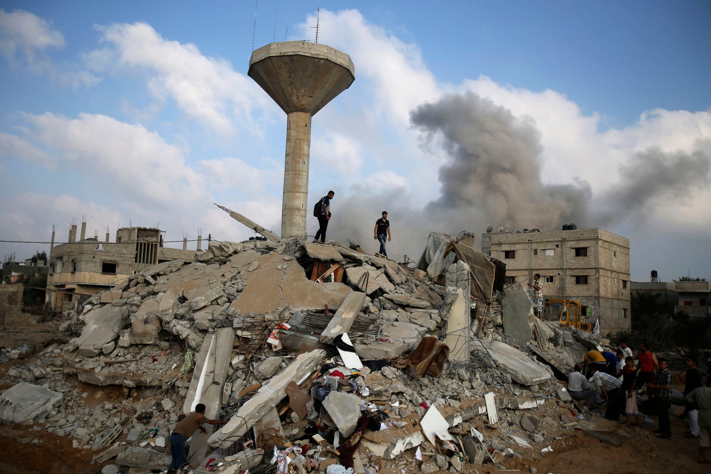 Palestinians search for victims as people gather atop the remains of a house, which witnesses said was destroyed in an Israeli air strike, in Rafah in the southern Gaza Strip on July 29, 2014.
