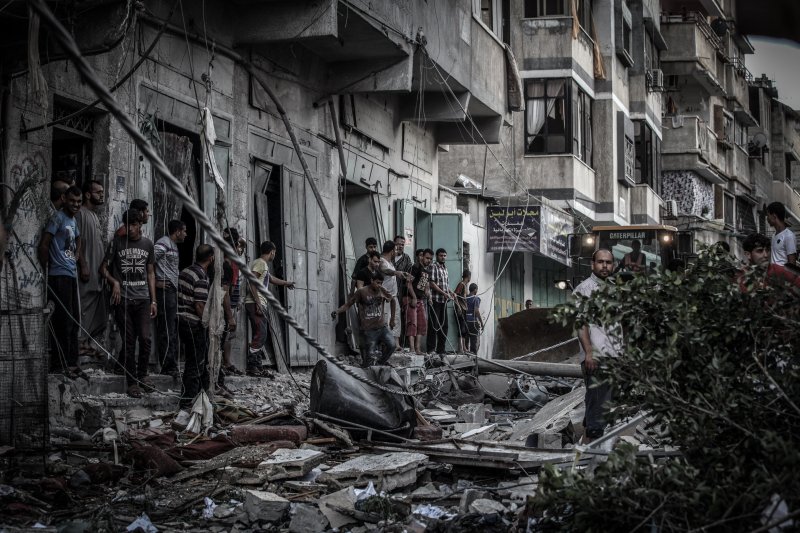 Palestinians inspect damage of an apartment building after it was hit by an Israeli missile strike in Gaza City, Friday, July 18, 2014.