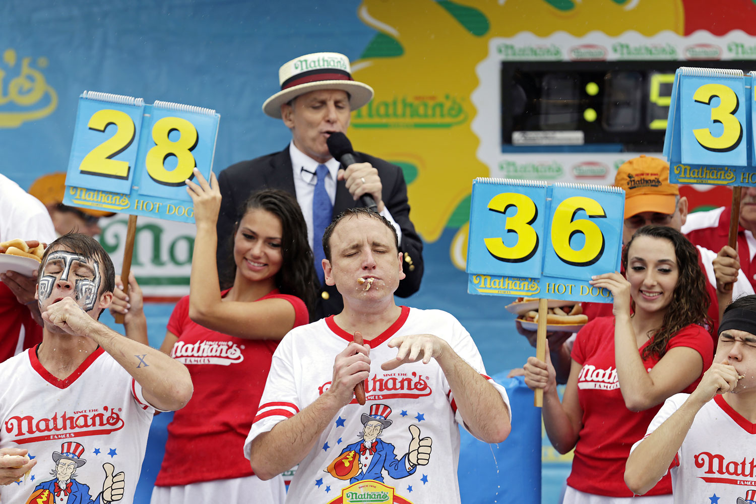 Champion eater's Joey Chestnut, center, Matt Stonie, right, and Tim 'Eater X' Janus, left, compete in Nathan's Famous Fourth of July International Hot-dog eating contest in Coney Island, July 4, 2014.