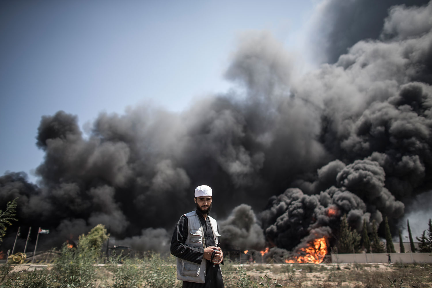 A Palestinian man walks in front of a fire raging at Gaza's main power plant on July 29, 2014, in Gaza City, following an overnight Israeli air strike (Oliver Weiken—EPA)