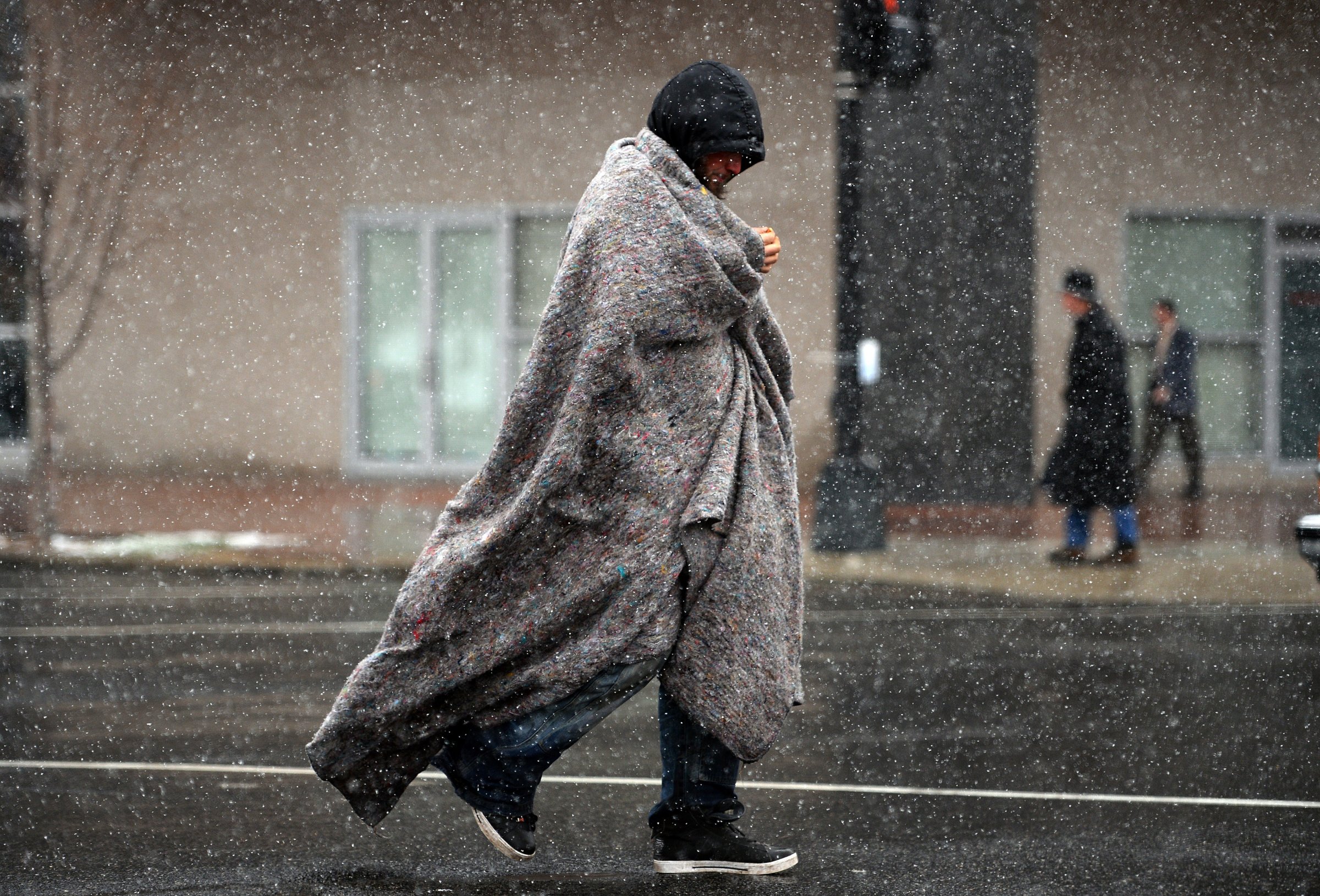 A man covers himself as he crosses a street under a snowfall in Washington, D.C. on March 25. 2014.