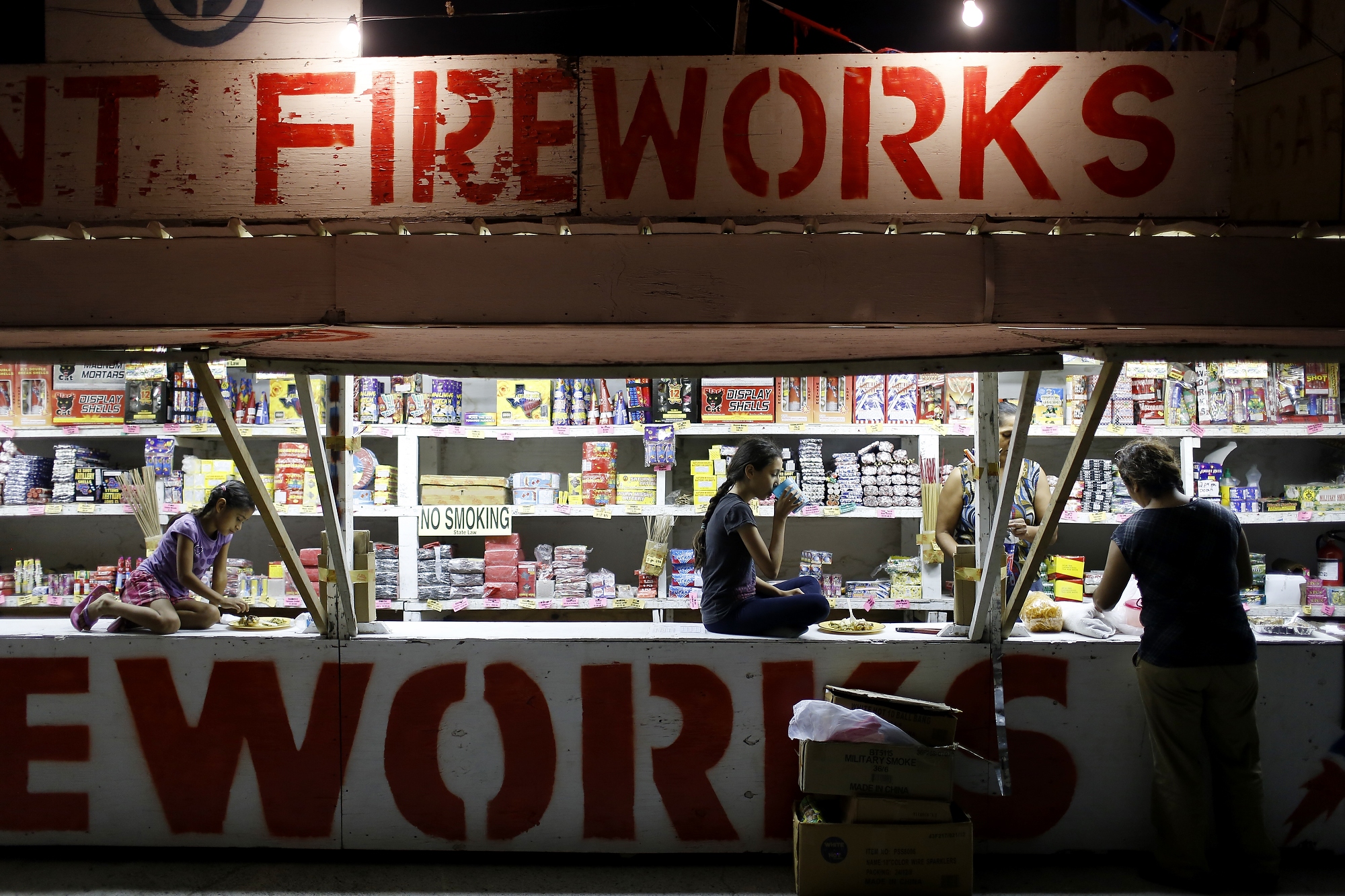 Cynthia Fuentes and Nelson Zamora have been selling fireworks since 1998.  WIth them is their daughter Elisabeth and granddaughters Briana, 11, and Jazlyn, 8, who share a meal at the fireworks stand in Hidalgo Texas, July 1, 2014.