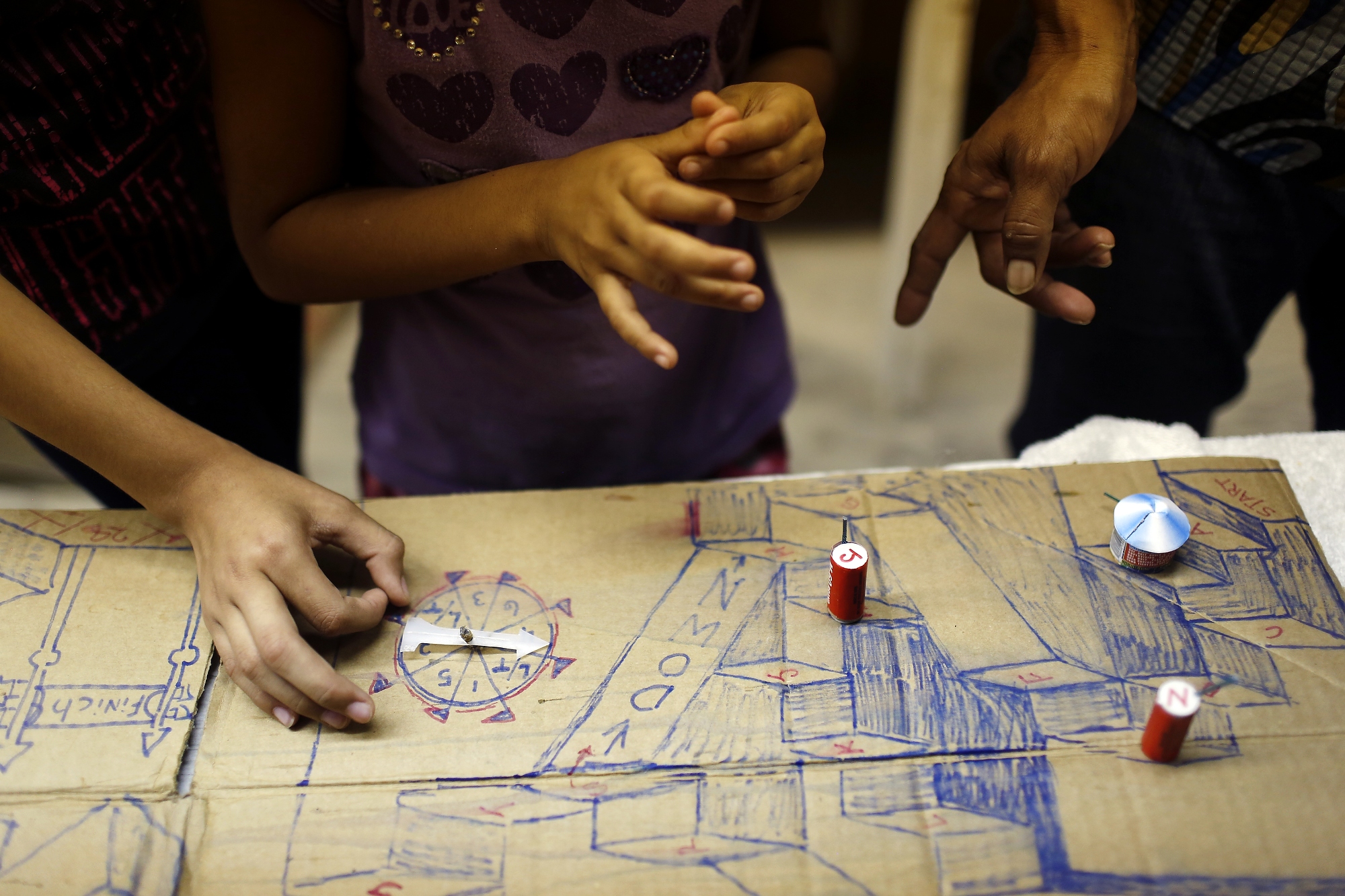 The young girls and Cynthia play a homemade board game with firecrackers as gamepieces, Hidalgo, Texas, July 1, 2014.