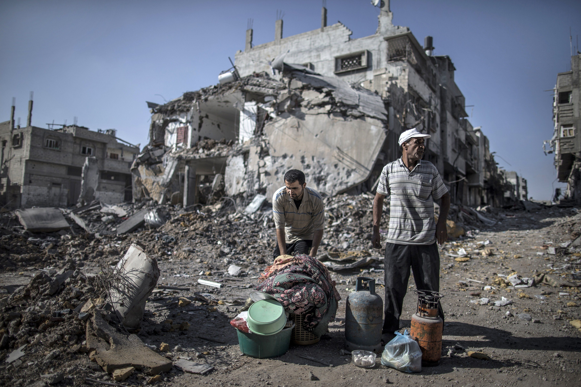 Palestinian men gather things they found in the rubble of destroyed buildings on July 27, 2014 in the Shejaiya residential district of Gaza City as families returned to find their homes ground into rubble by relentless Israeli tank fire and air strikes.