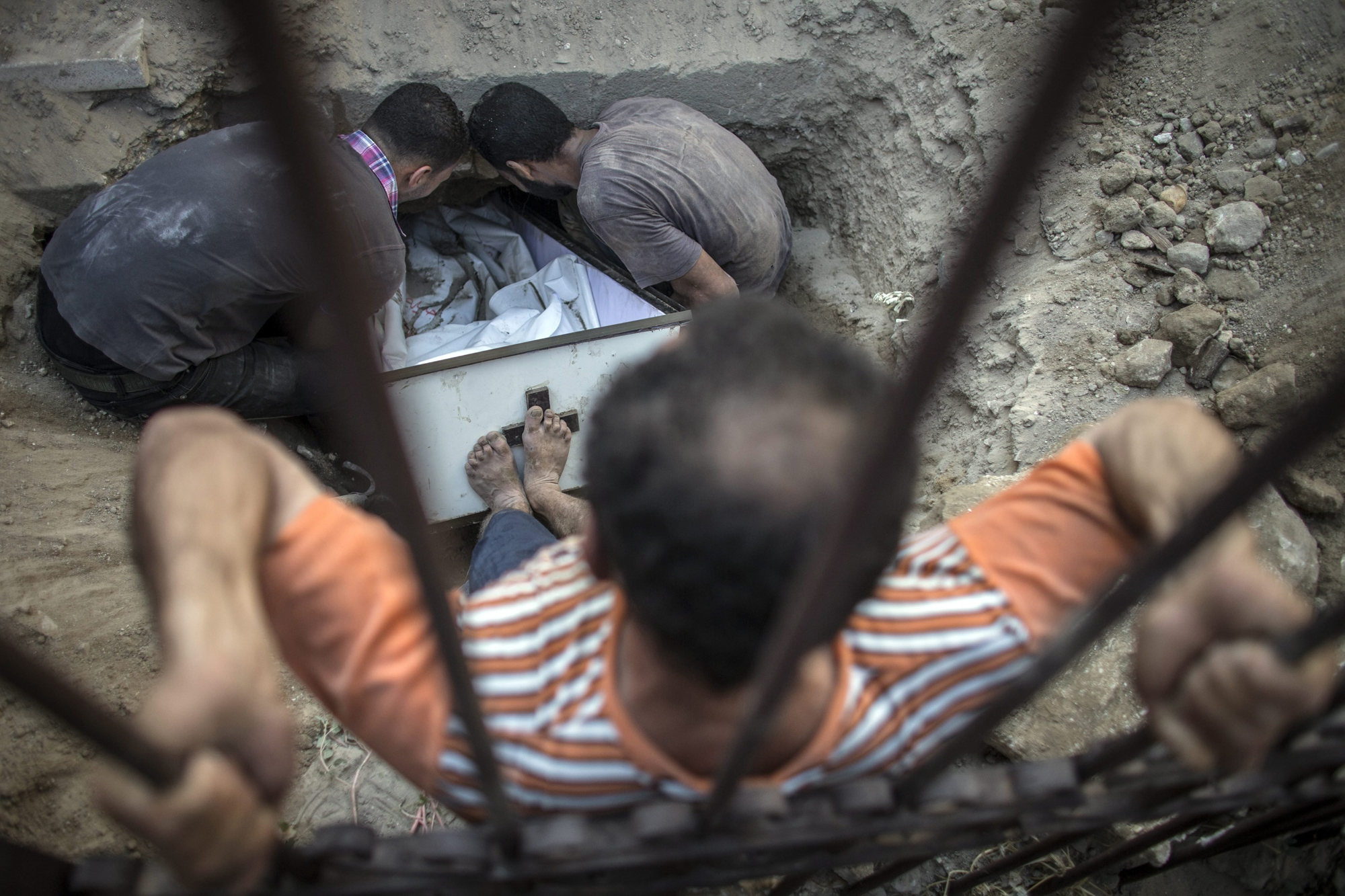 A Palestinian Christian man from Gaza tries to push the coffin of Jalila Ayad in her grave during her funeral on the small and overcrowded cemetery of the St. Porfirius church in Gaza City, July 27, 2014.