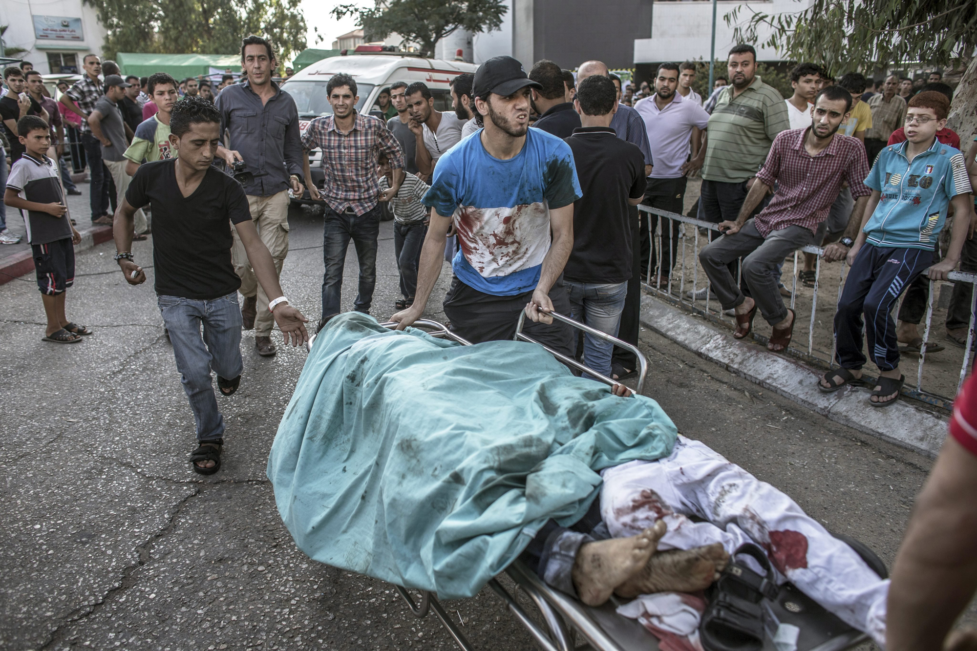 Palestinian men rush the bodies of two dead children from the emergency room to the morgue of Shifa hospital in Gaza City, July 28, 2014.