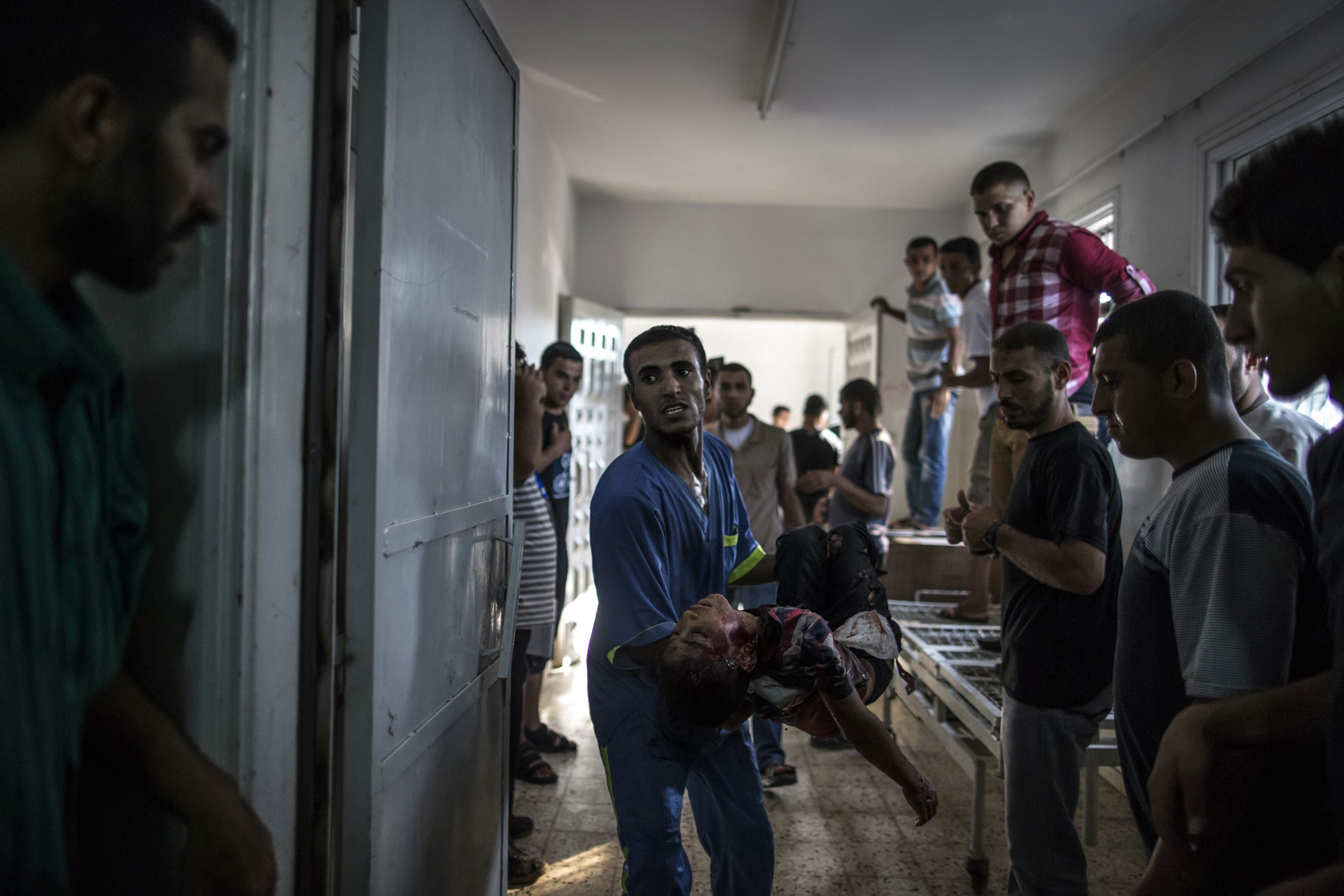 A Palestinian medic carries the body of a child, killed in an explosion in a public playground on the beachfront of Shati refugee camp, in the morgue of Shifa hospital in Gaza City on July 28, 2014.
