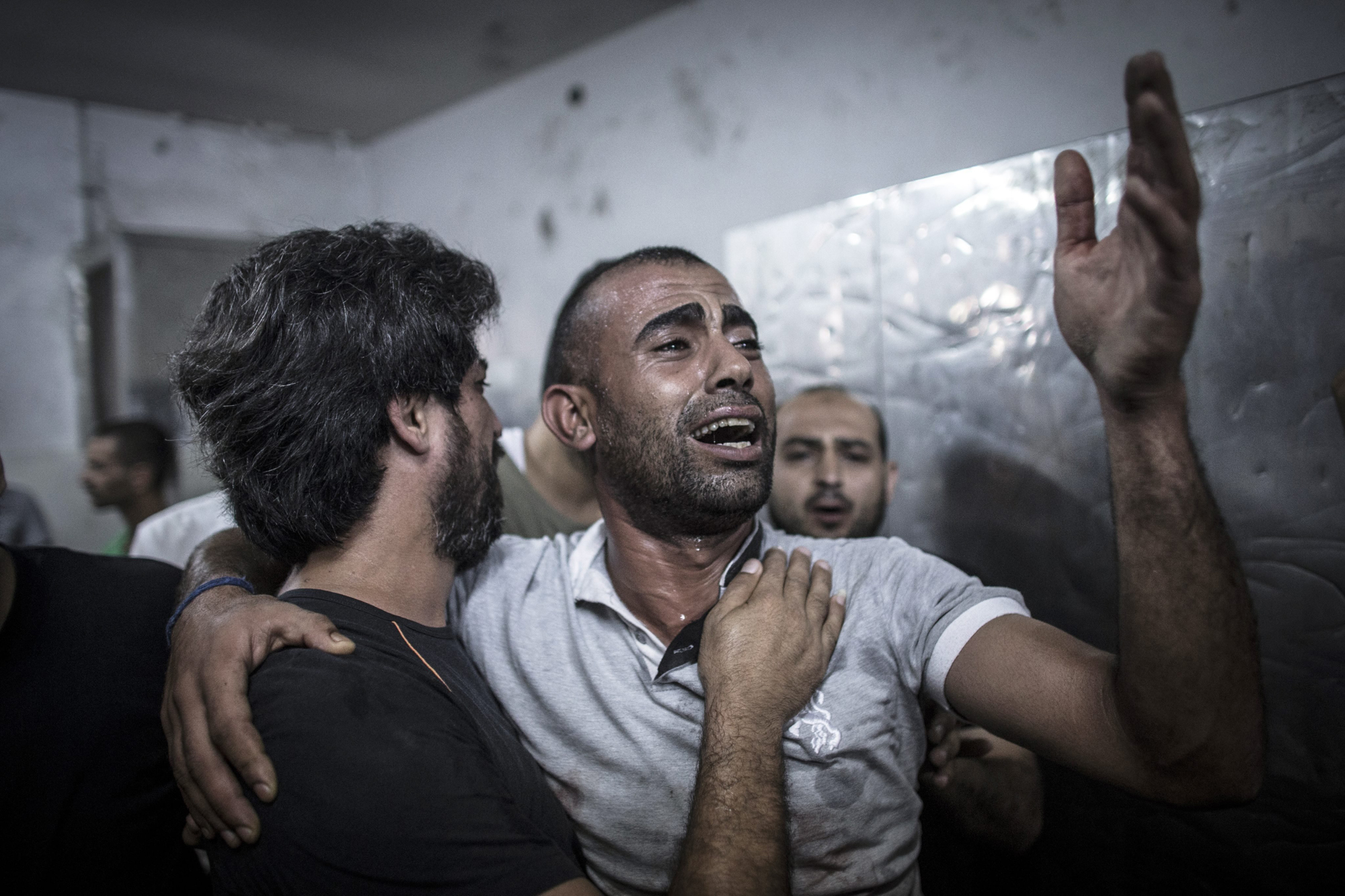 Palestinian men react after the bodies of several children arrived in the morgue of the Shifa hospital in Gaza City, July 28, 2014.
