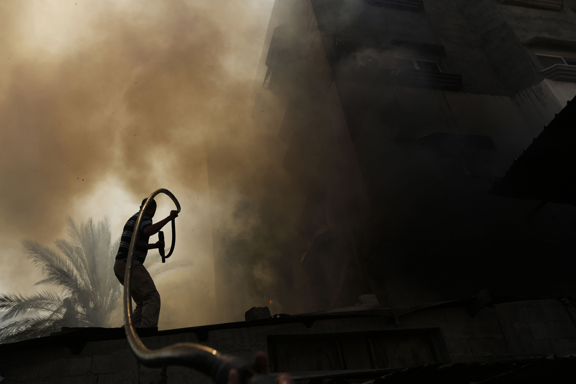 A Palestinian man battles a building on fire following several Israeli strikes on Gaza City on July 30, 2014.