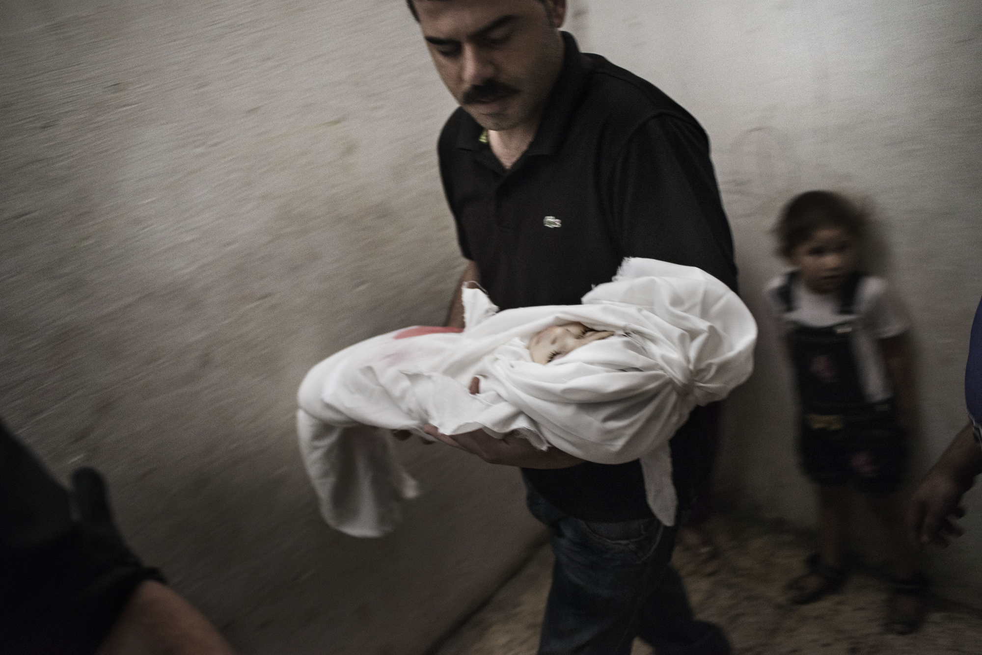 The father of 18-month-old Razel Netzlream, who was fatally wounded during an air strike, carries her body right before her funeral in Rafah, Gaza Strip, on July 18, 2014 (Alessio Romenzi)