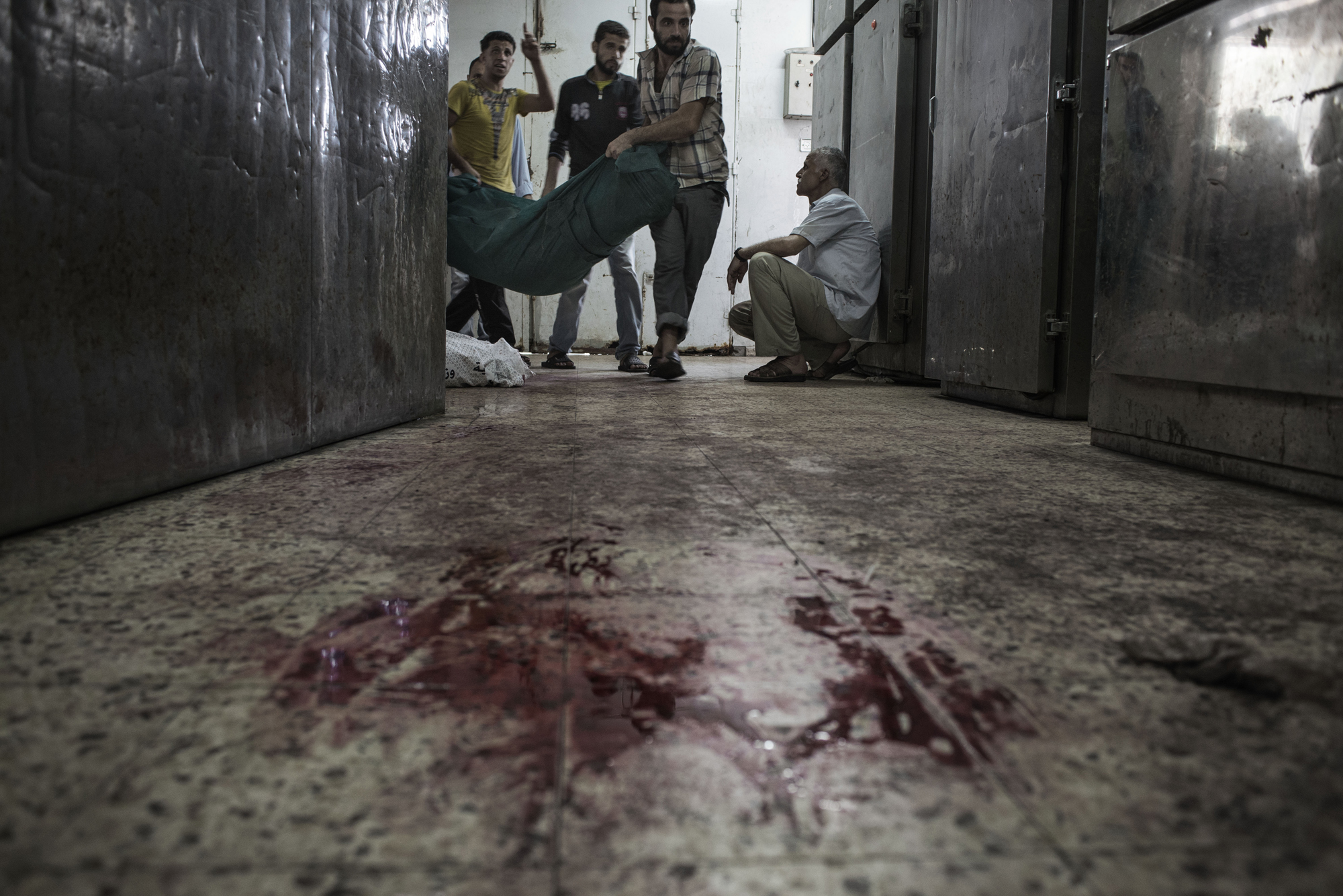 Palestinians carry a body inside the Shifa Hospital morgue, in Gaza City. July 20, 2014.