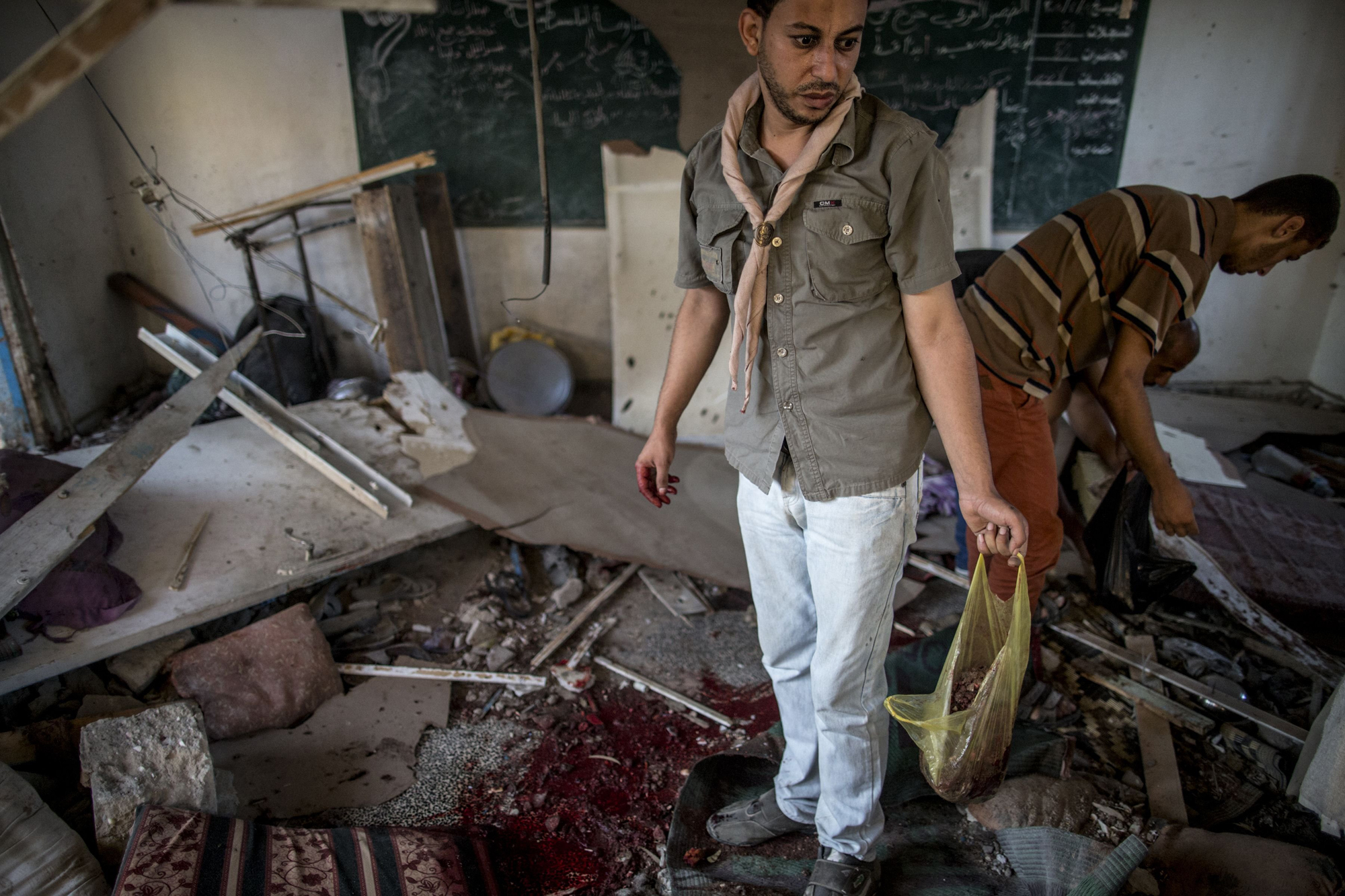 Palestinians collect human remains from a classroom inside a UN school in the Jabalia refugee camp after the area was hit by shelling on July 30, 2014.