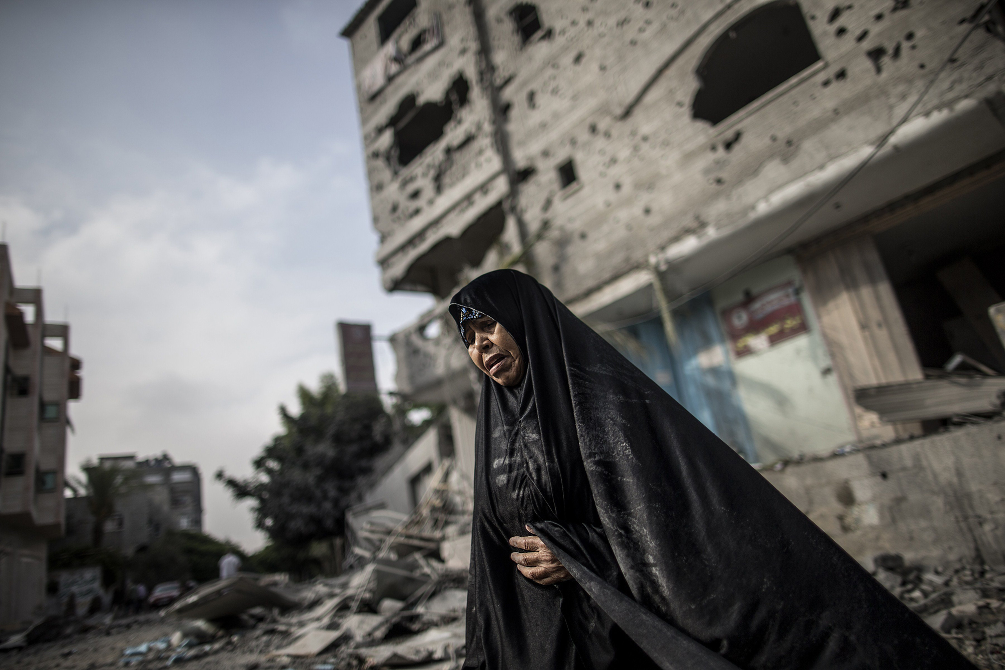 A Palestinian woman stands in front of buildings damaged by Israeli bombardment in the Jabalia district of the northern Gaza Strip on July 24, 2014.