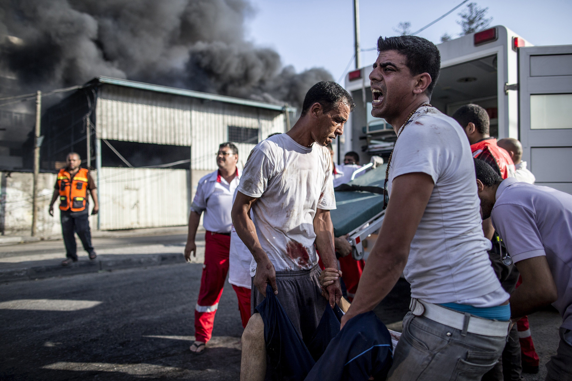 Palestinian emergency personnel and civilians evacuate victims of an Israeli air strike on a market place in the Shejaiya neighborhood near Gaza City, on July 30, 2014.