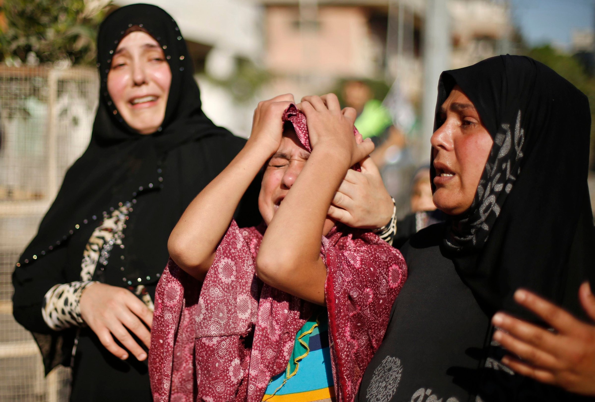 Sister of a Palestinian boy from Baker family, whom medics said was killed along with three other children from same family by a shell fired by Israeli naval gunboat, mourns during their funeral in Gaza City