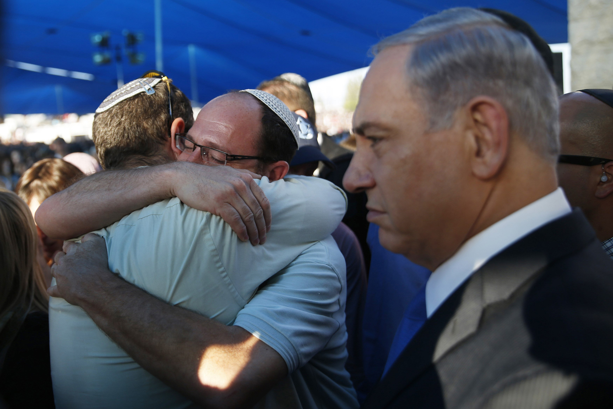 Israeli Prime Minister Benjamin Netanyahu stands next to Avi Fraenkel and Ofir Shaer, fathers of two of the three Israeli teens who were abducted and killed in the occupied West Bank, as they hug during their sons' joint funeral in the Israeli city of Modi'in July 1.